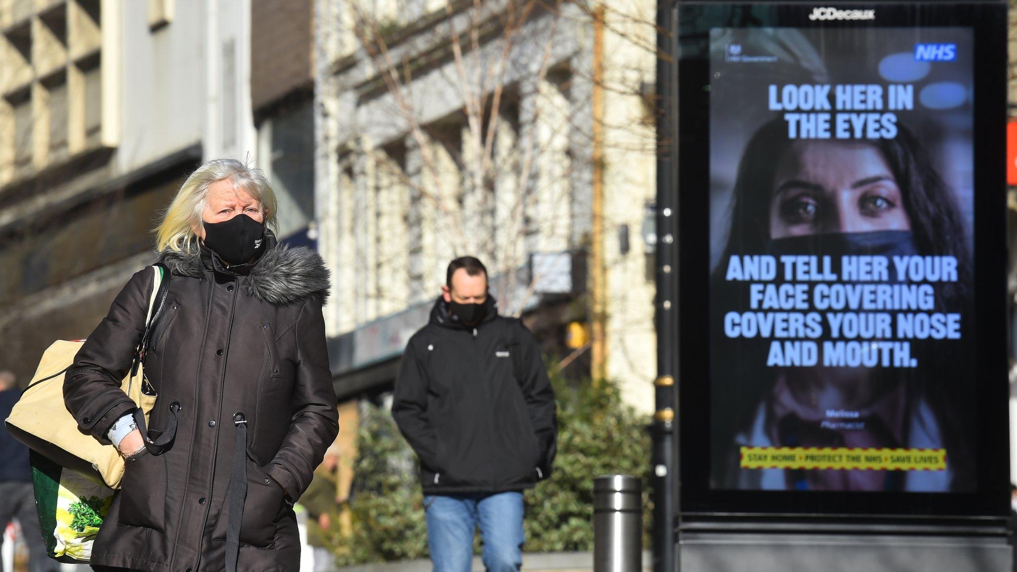 A woman walks past a coronavirus sign in Bradford City centre