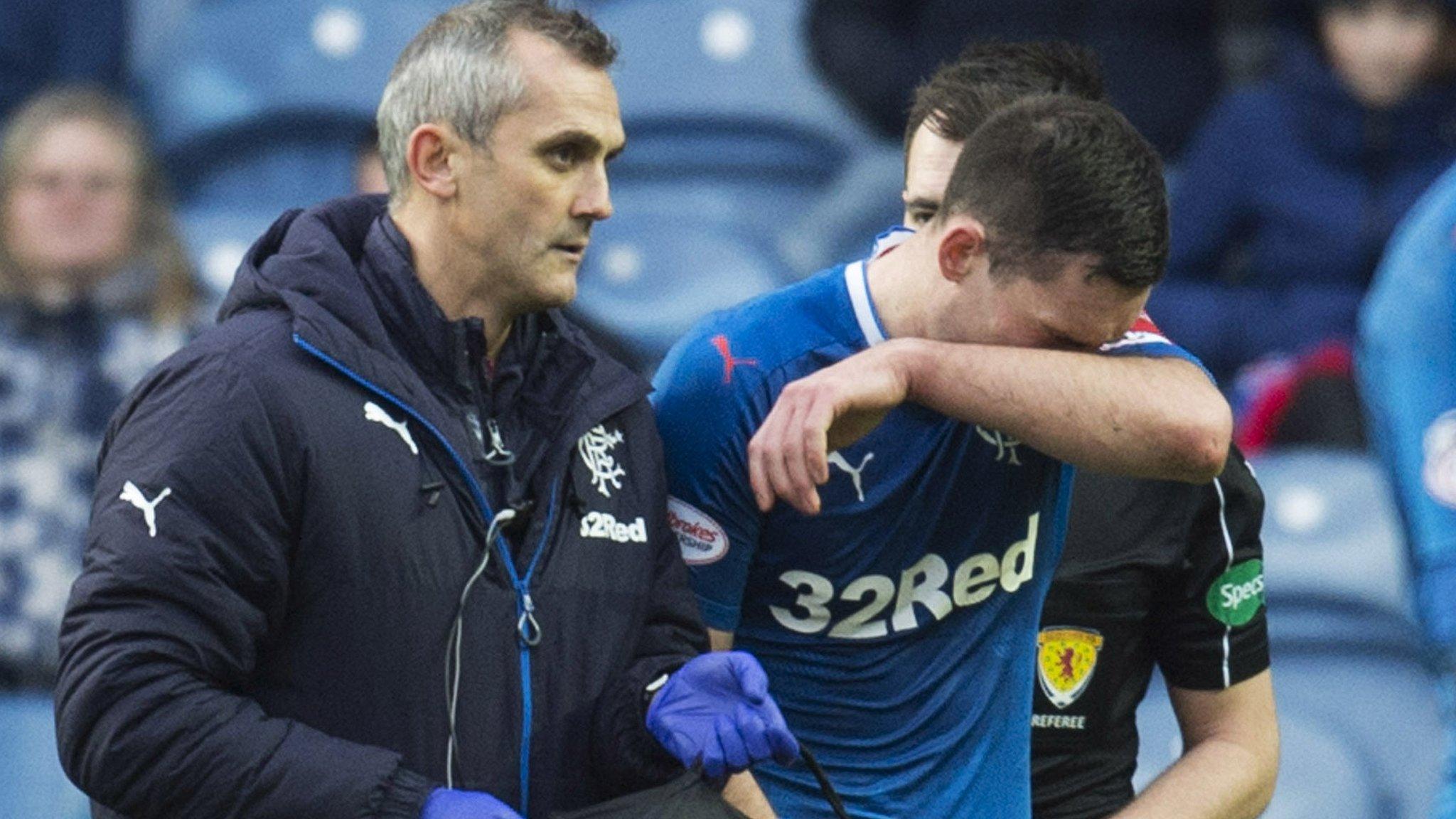 Lee Wallace holds his arm in front of his face as he receives treatment against ICT