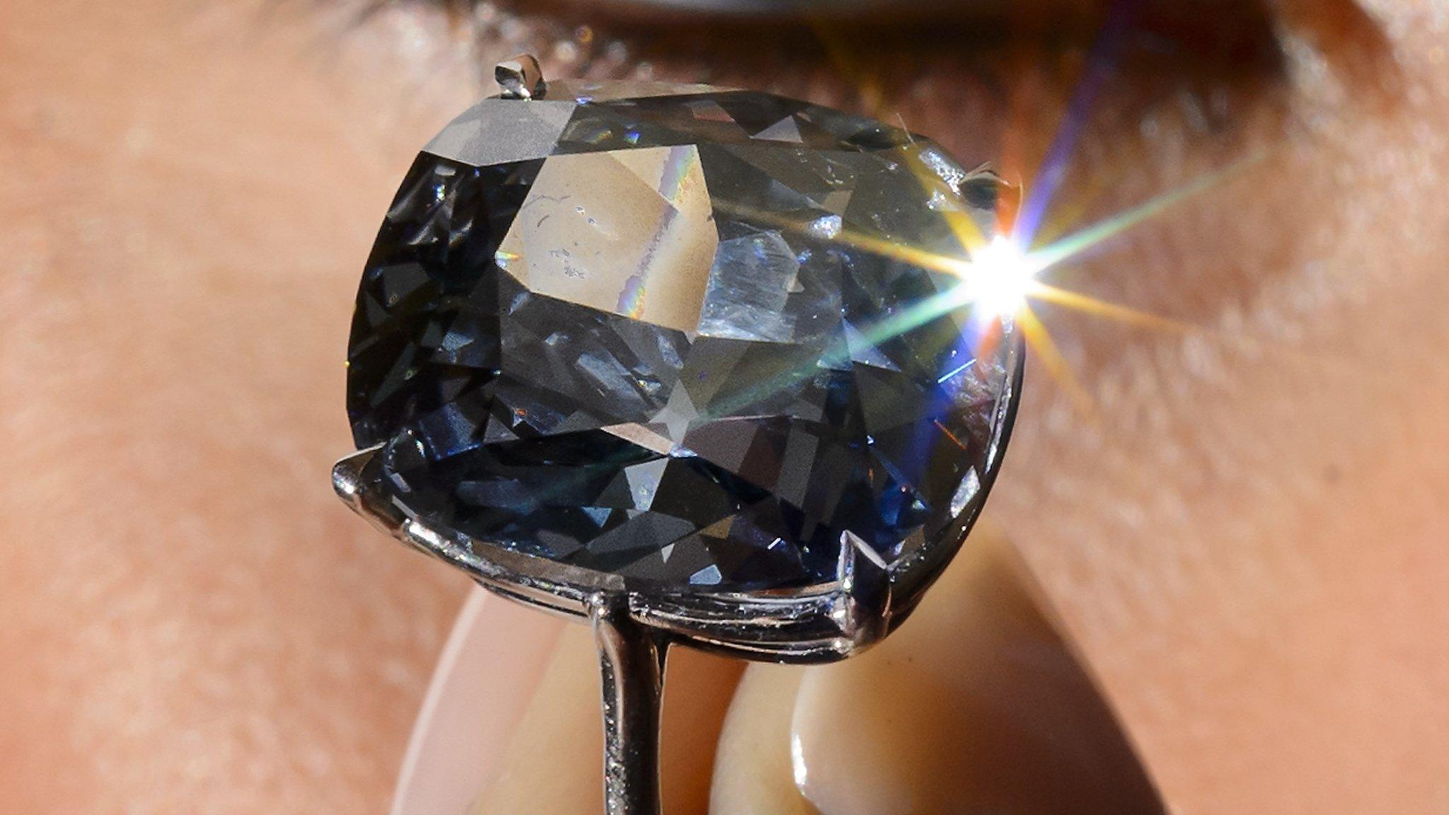 A picture taken on November 4, 2015 shows a model holding a 12.03-carat blue diamond during a press preview by auction house Sotheby"s in Geneva