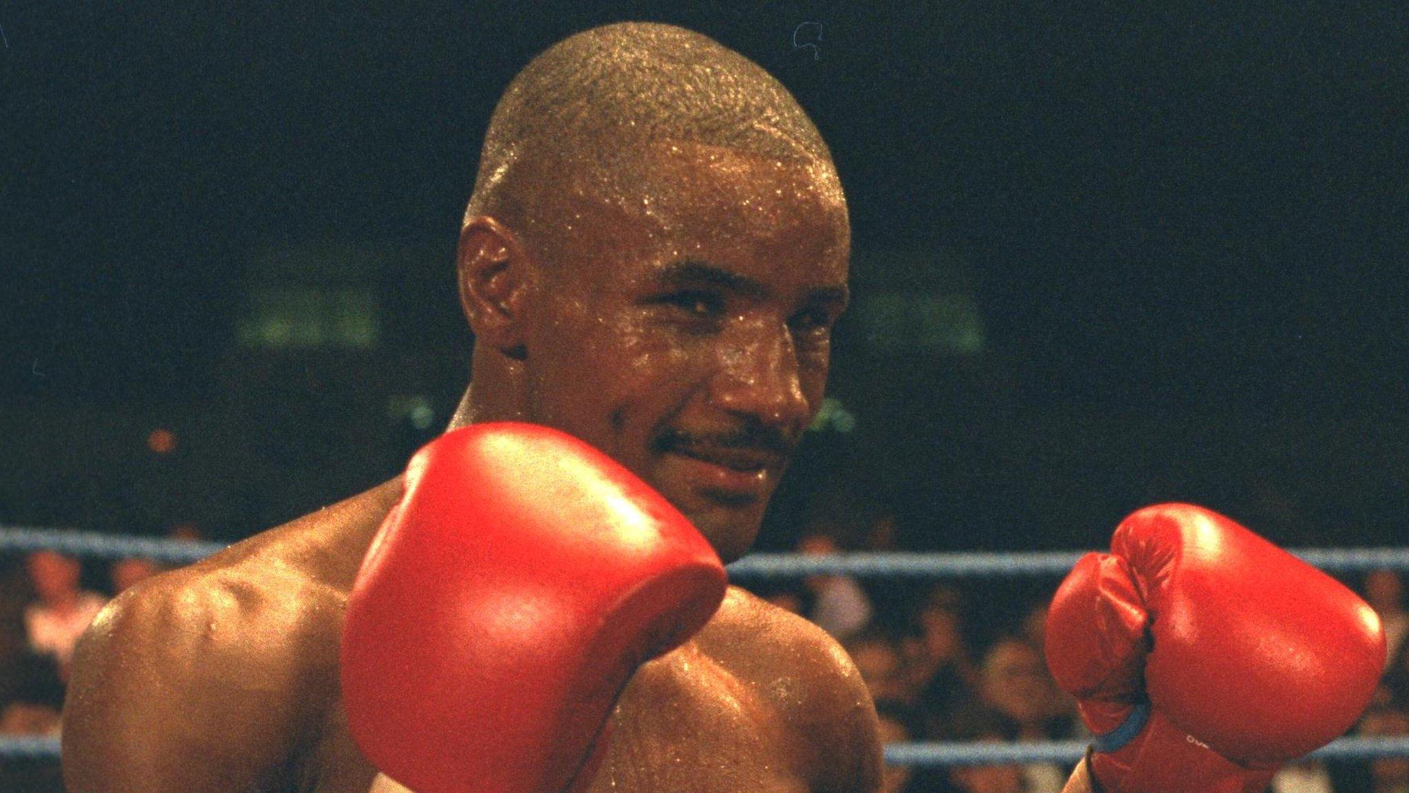 Boxer Steve Robinson poses for a photograph inside the ring. He is smiling in the photo while also looking very sweaty