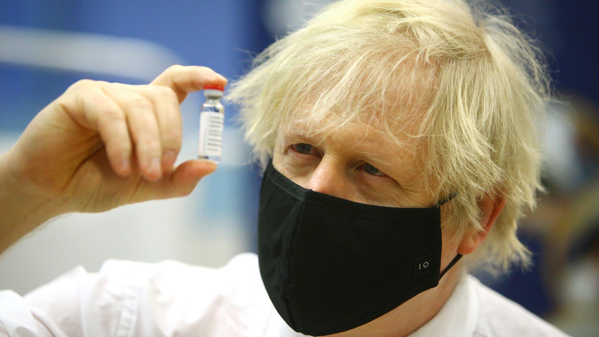 Boris Johnson holds up a vaccine vial