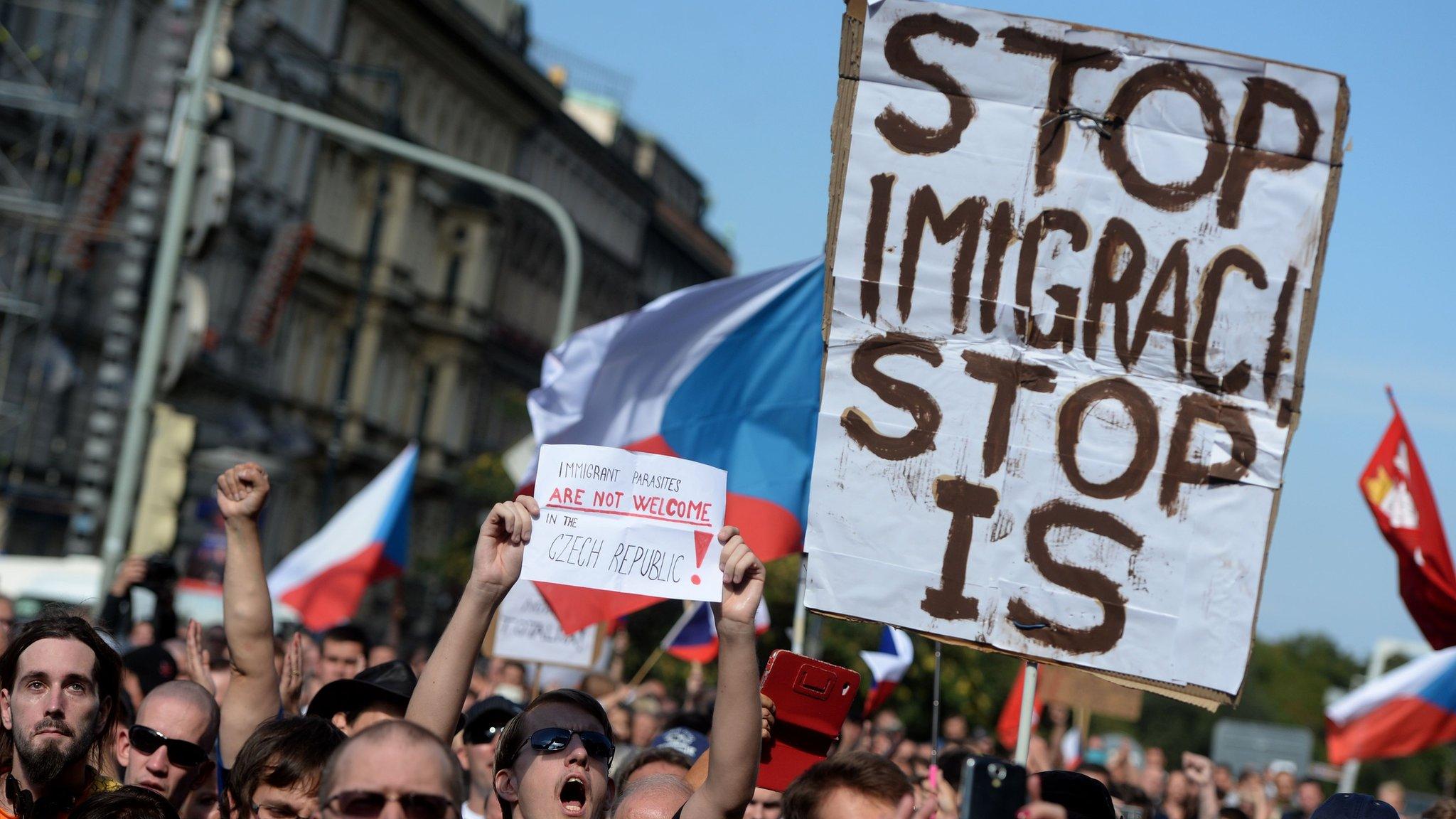 Protestors in Prague hold up an anti-immigration and ant-IS placard