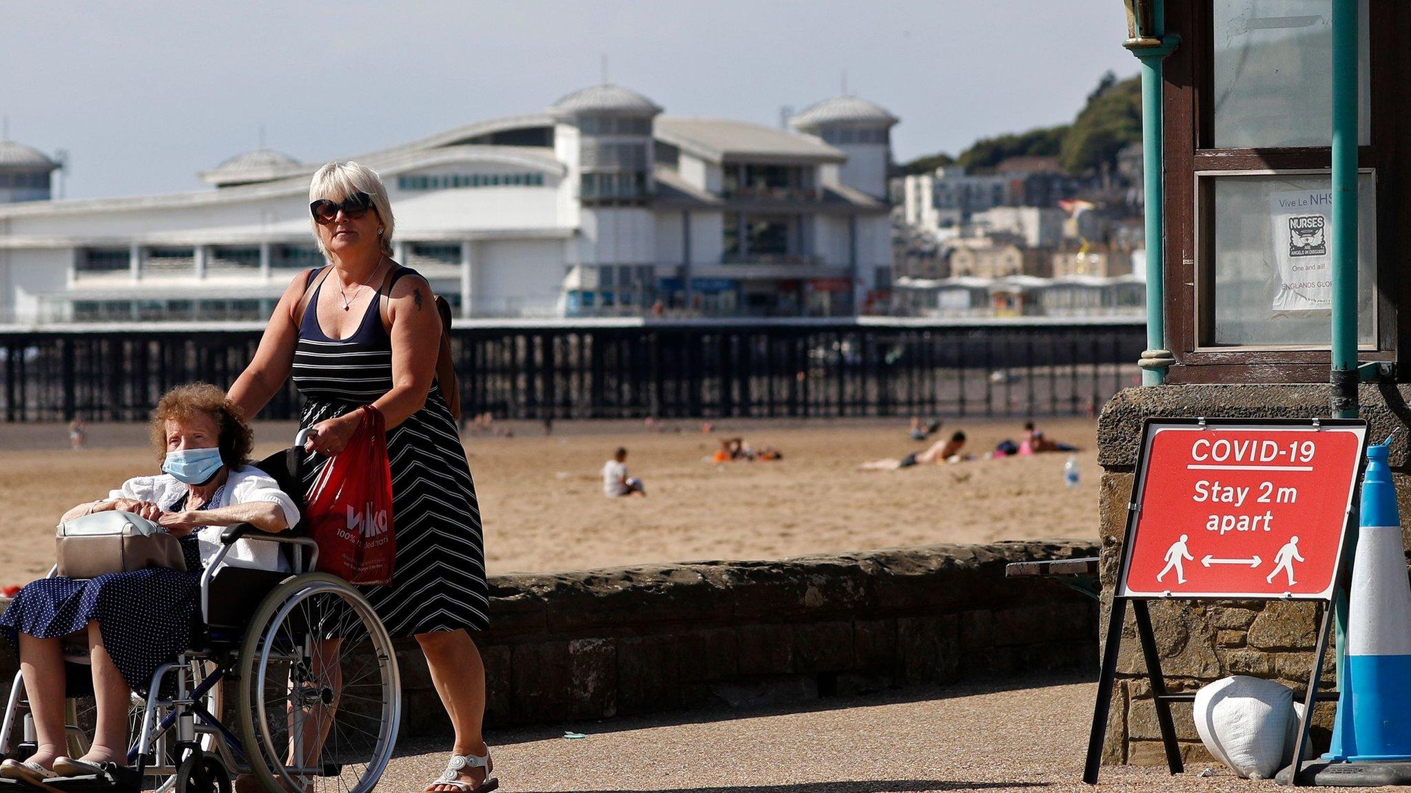 Two women pass a coronavirus warning sign at Western-super-Mare