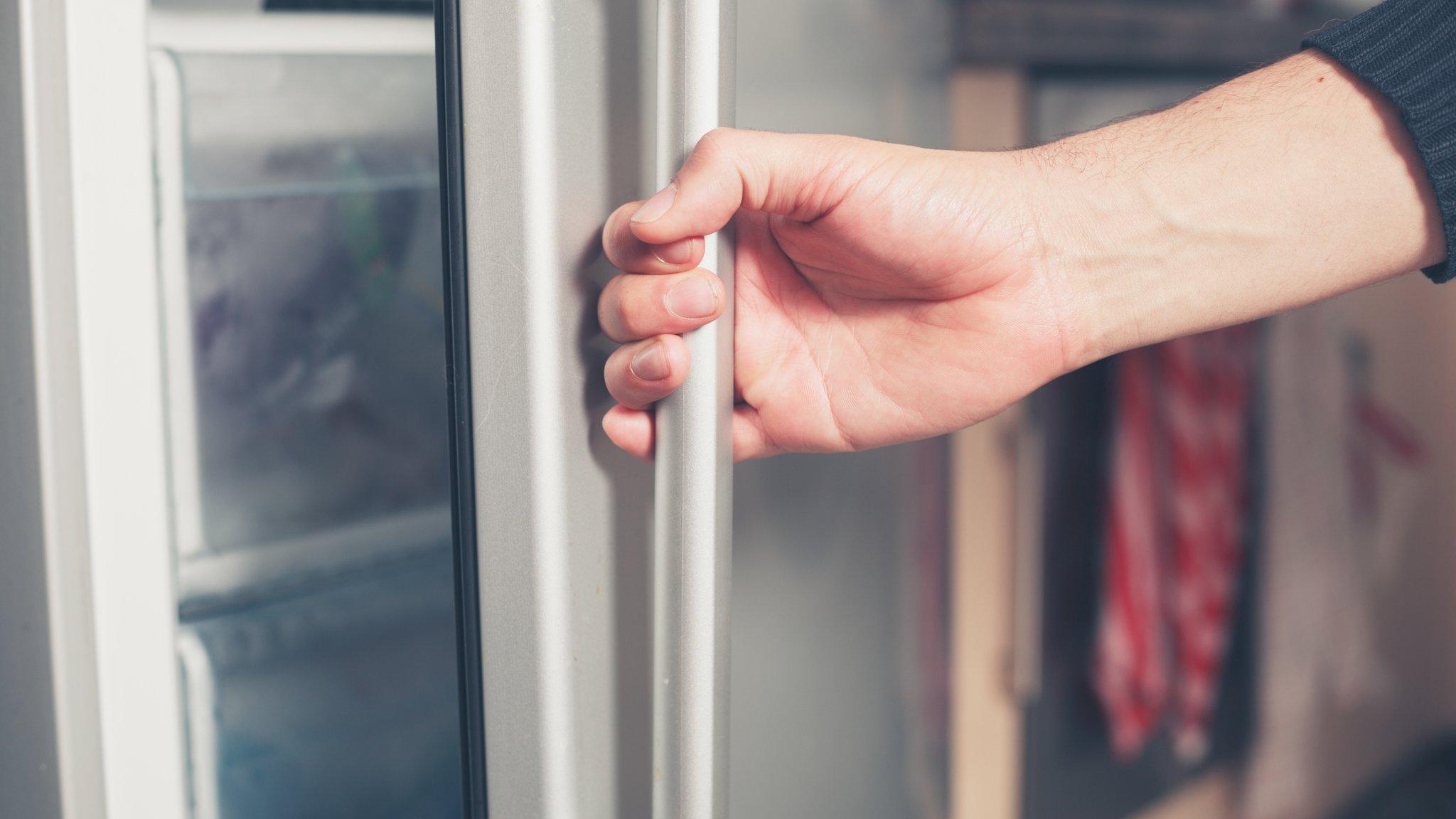 man opens fridge door