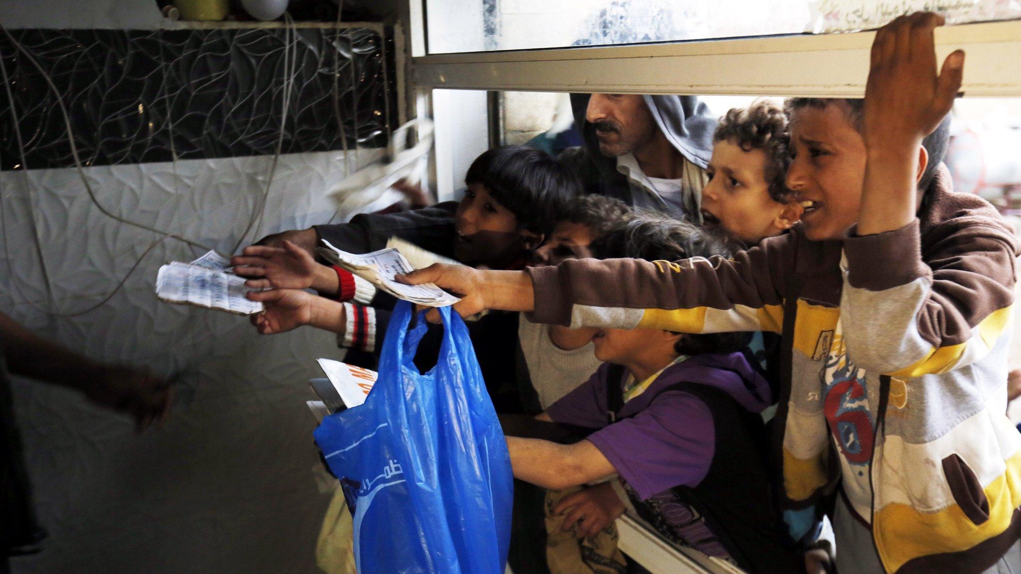 people wait to get their families" free food ration from a charity kitchen in Sanaa