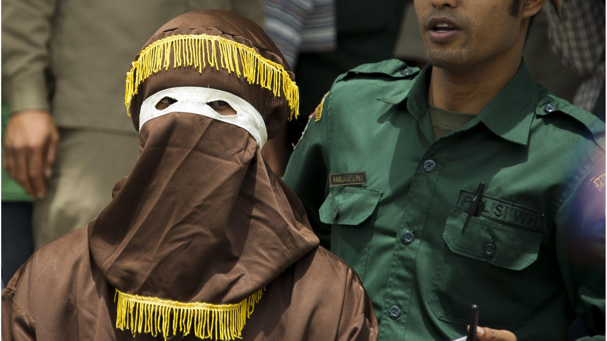 An Indonesian Sharia police officer prepares to administer a public caning