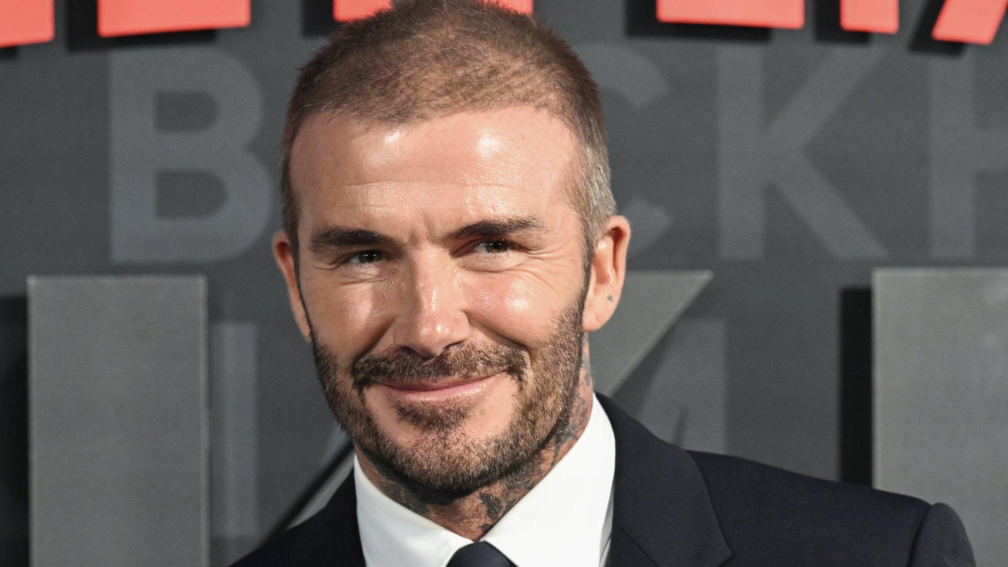 David Beckham smiling in a suit and tie