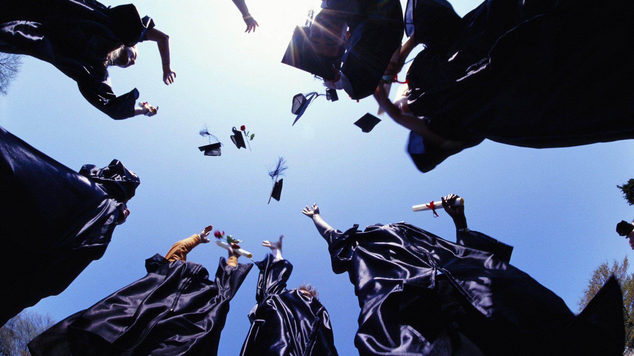 Graduates throwing mortar hats into the air