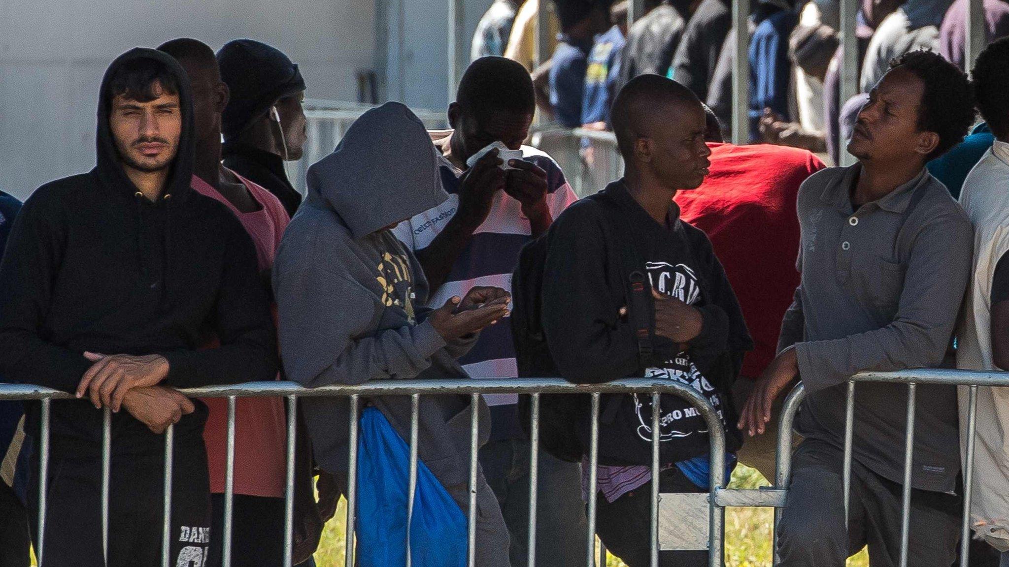 Migrants queue to receive food