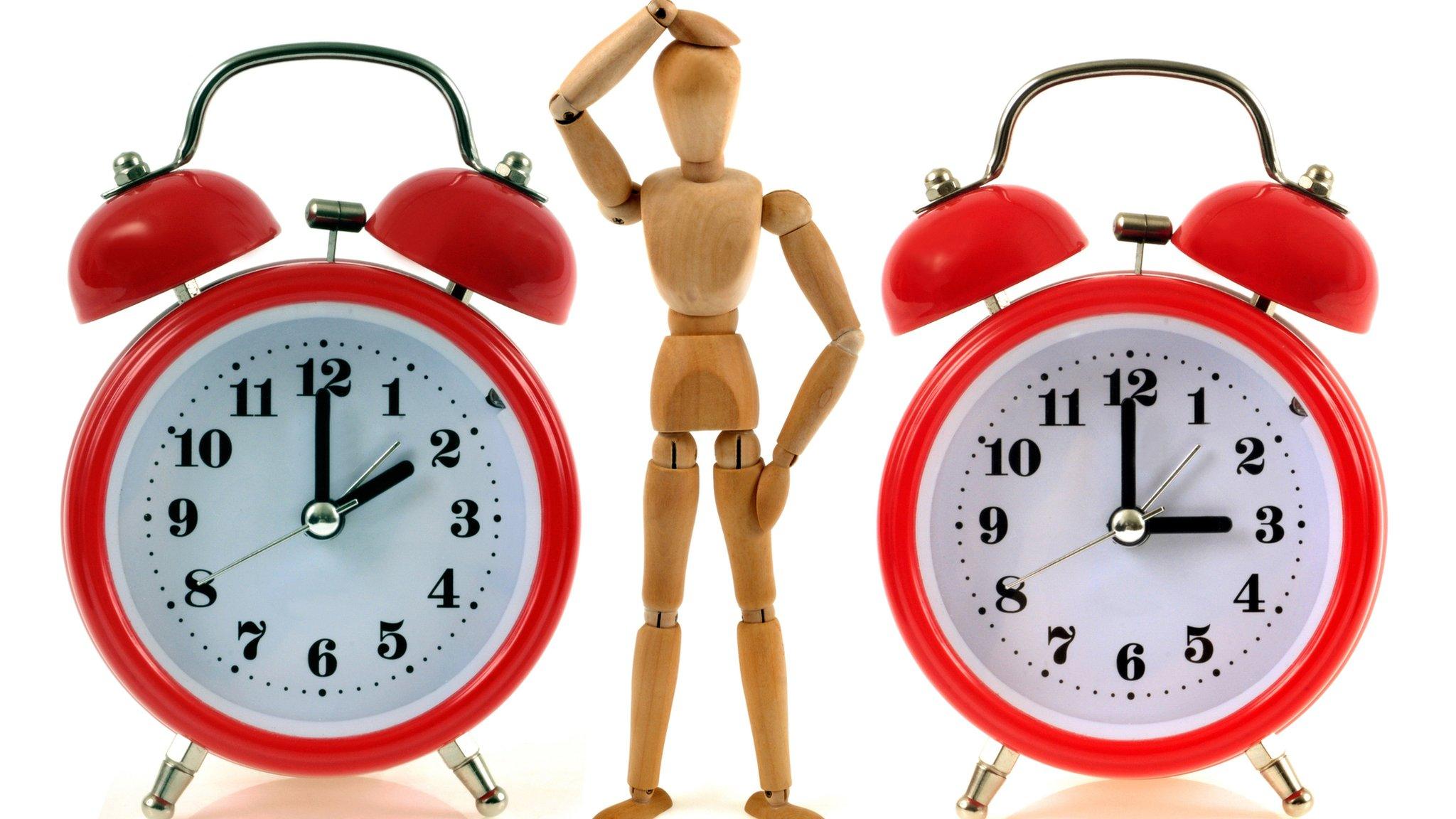 A mannequin looks puzzled beside two clocks