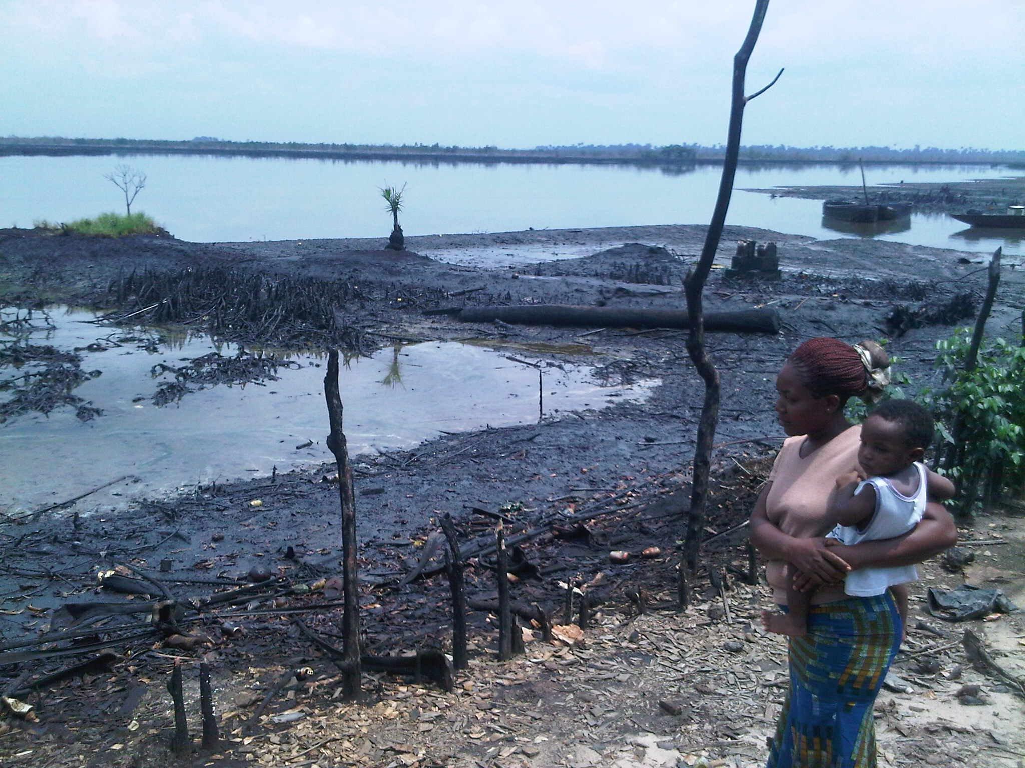 Lady and baby looking at an oil spill