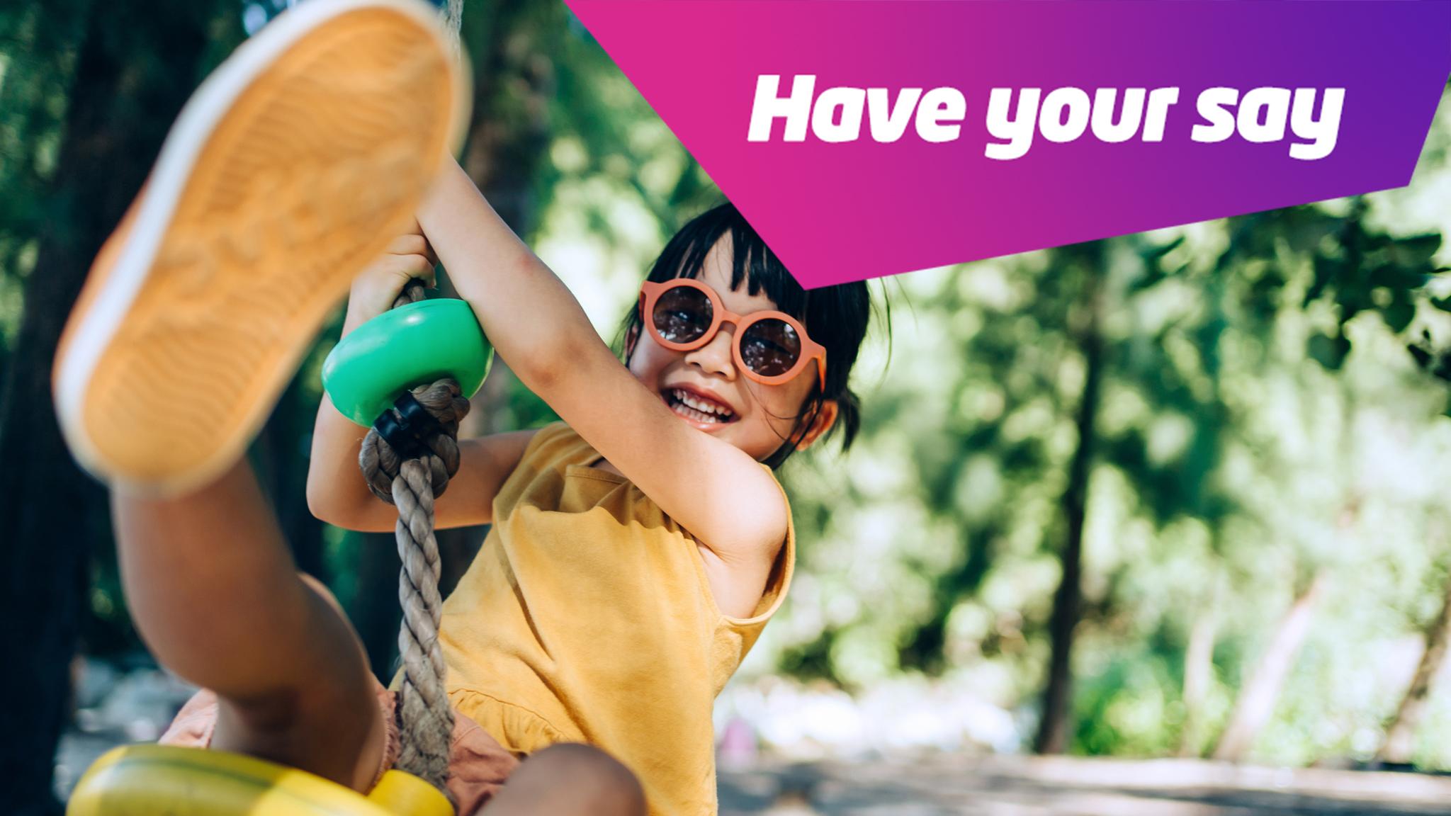 kid swinging with sunglasses on smiling in a forest