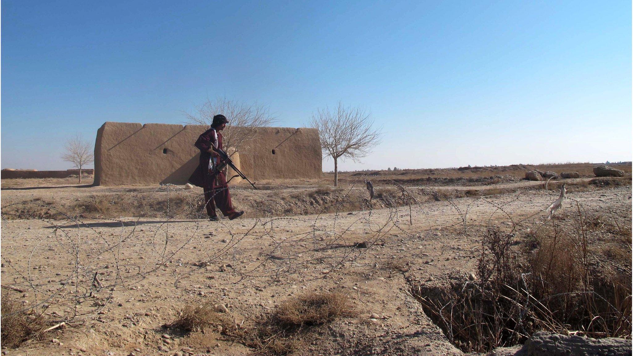 A member of the Afghan Local Police (ALP) forces stands guard on a roadside in the Nawar area of Marjah district, Helmand province, Afghanistan (23 December 2015)