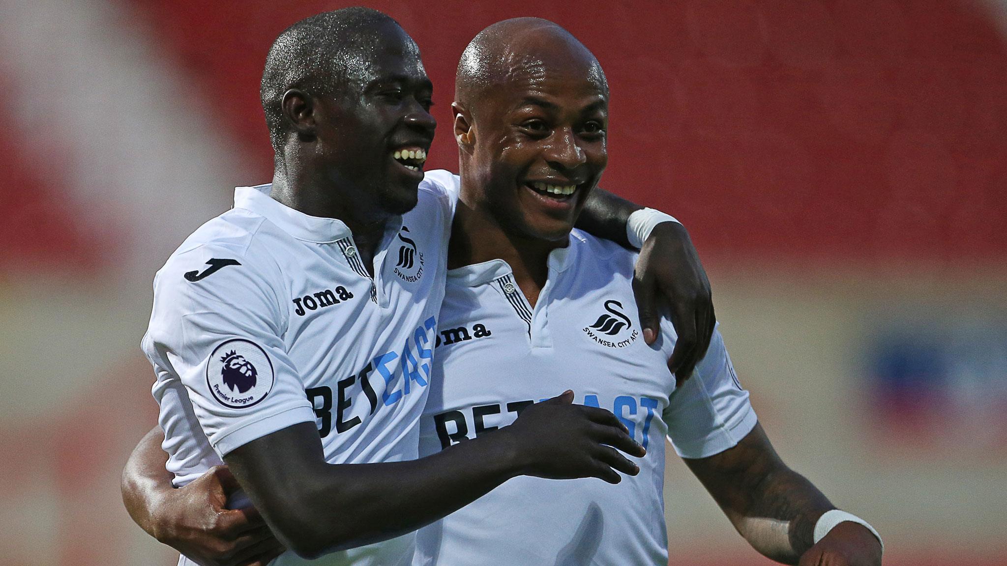 Modou Barrow and Andre Ayew celebrate a goal for Swansea against Swindon