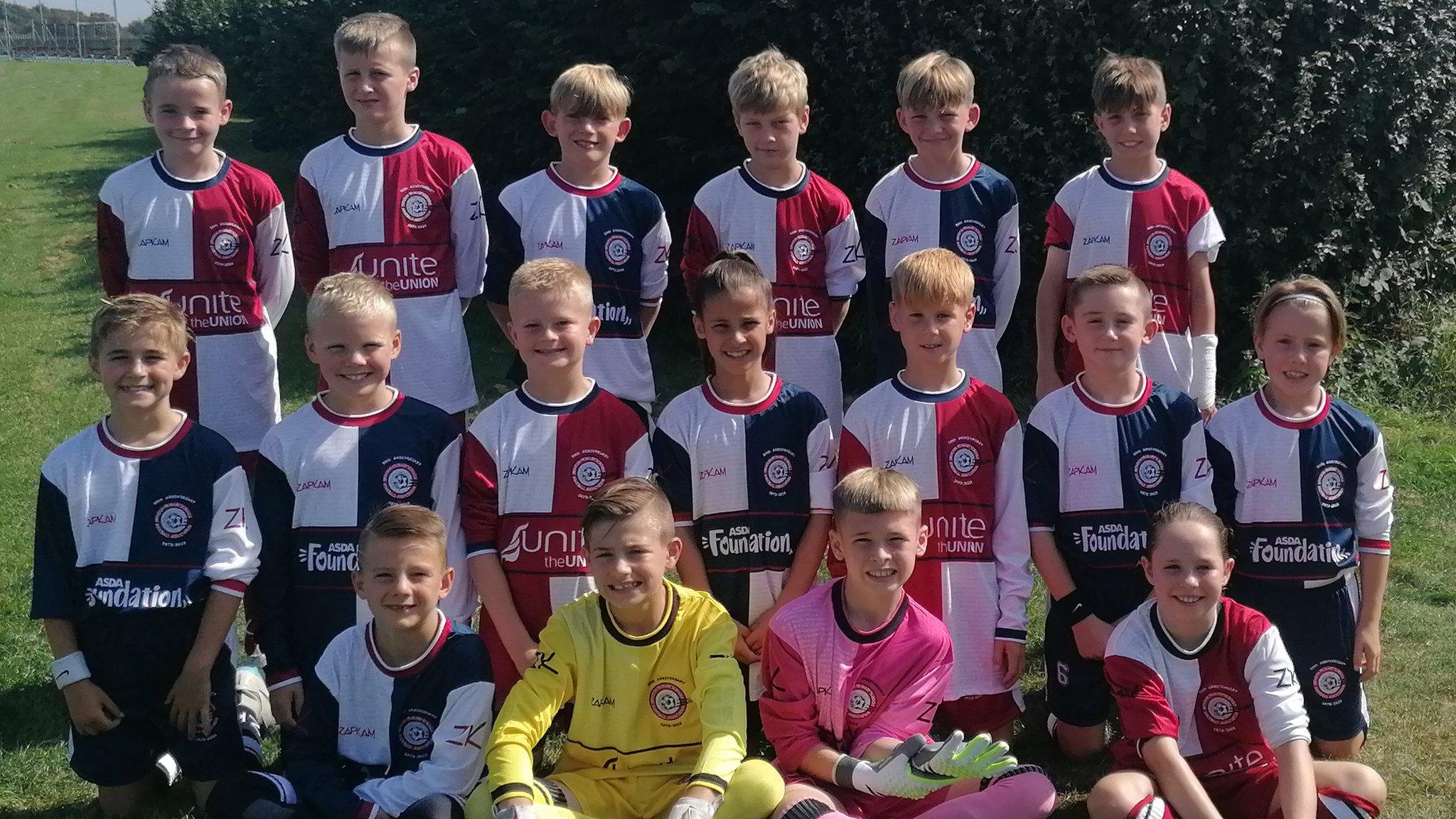 Children smiling as they pose for their football team photo