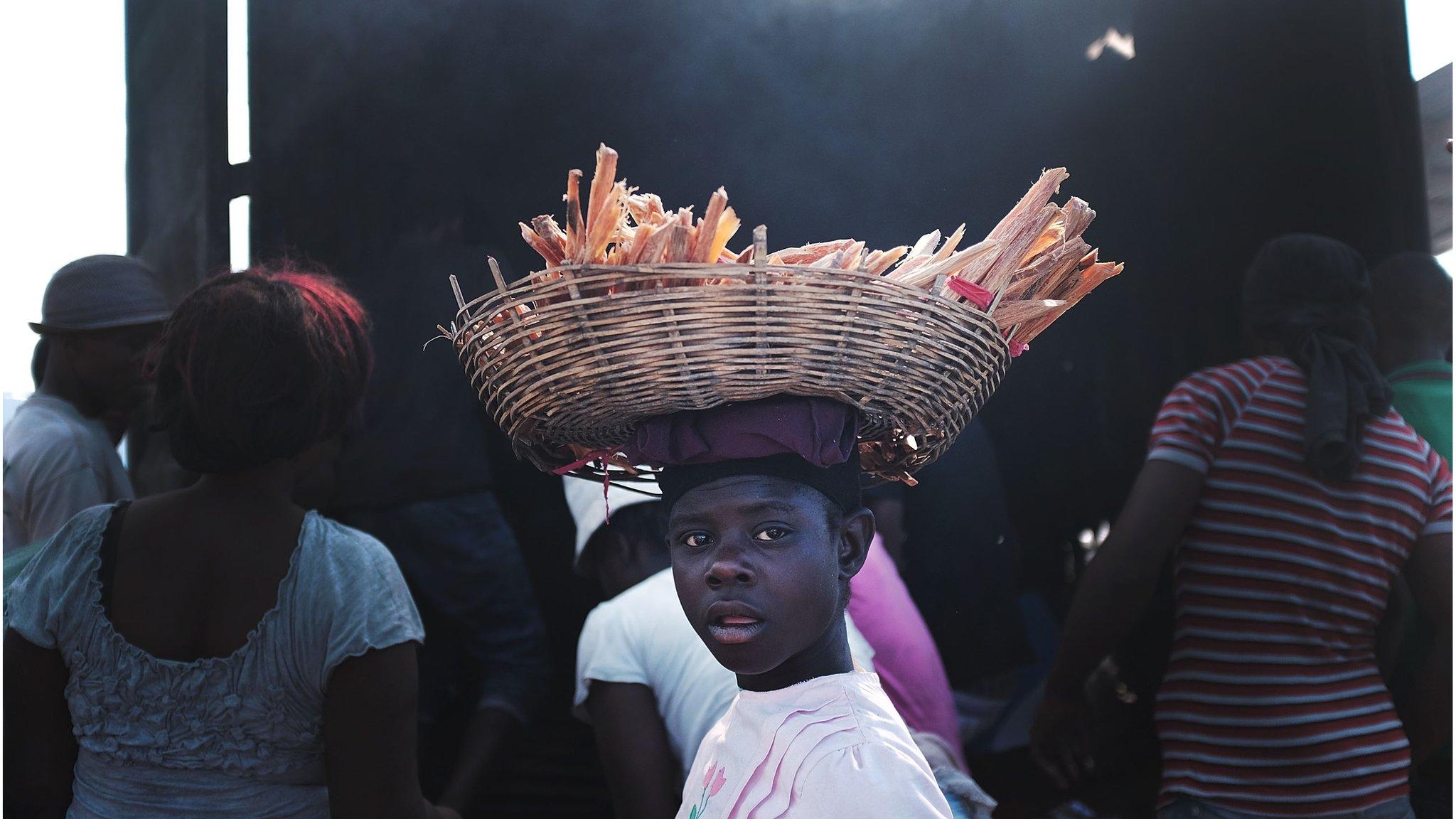 A trader carries a basket of food from the burnt out remains of the market.