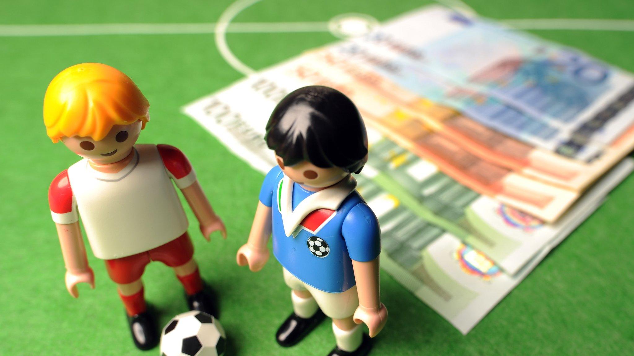 Figurines of footballers standing near a pile of cash