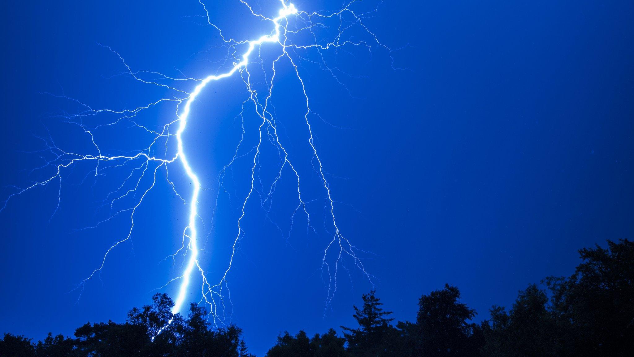 Lightning striking behing trees