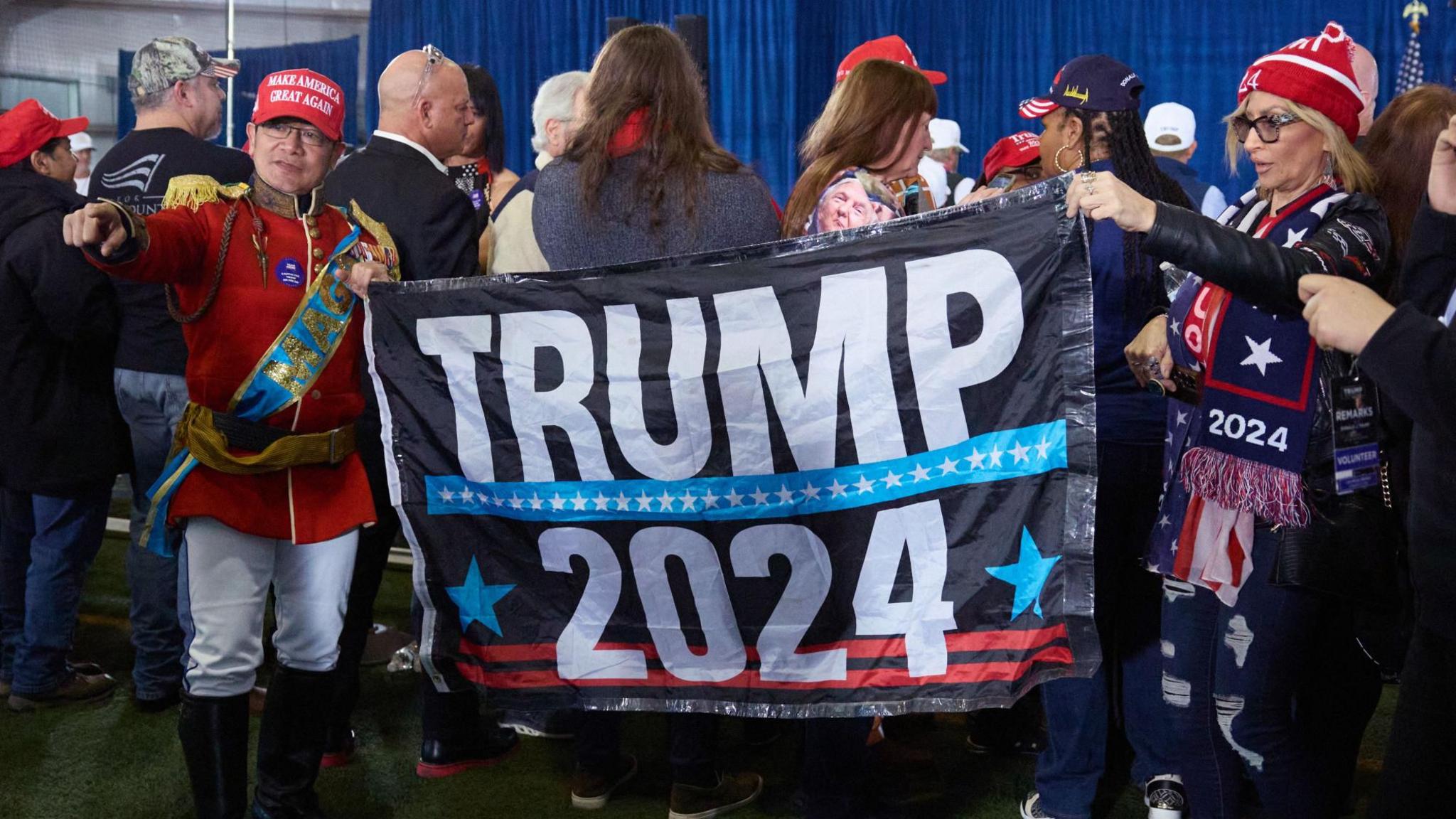 Supporters hold a Trump 2024 sign