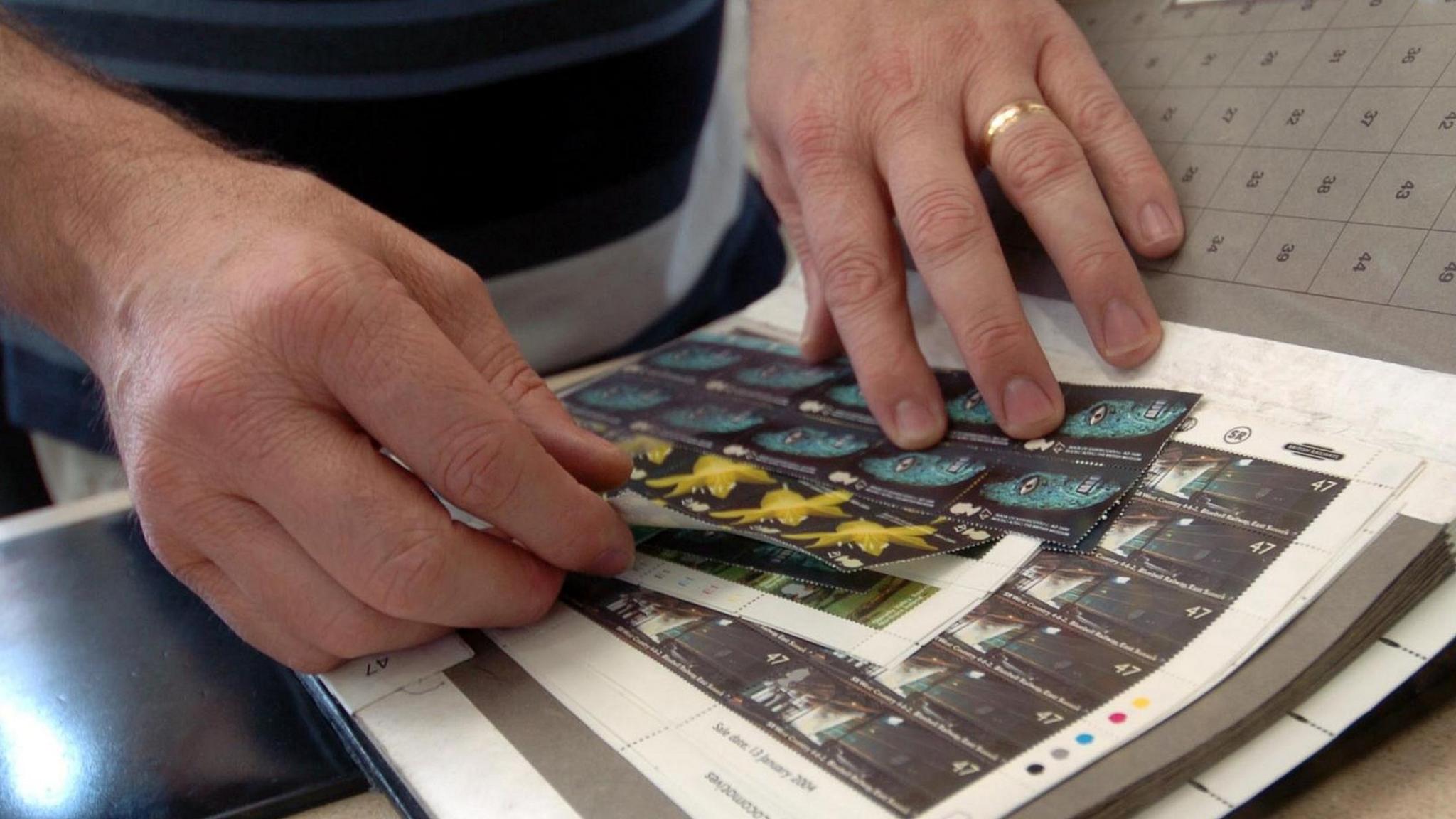 Man removing postage stamps from a larger book