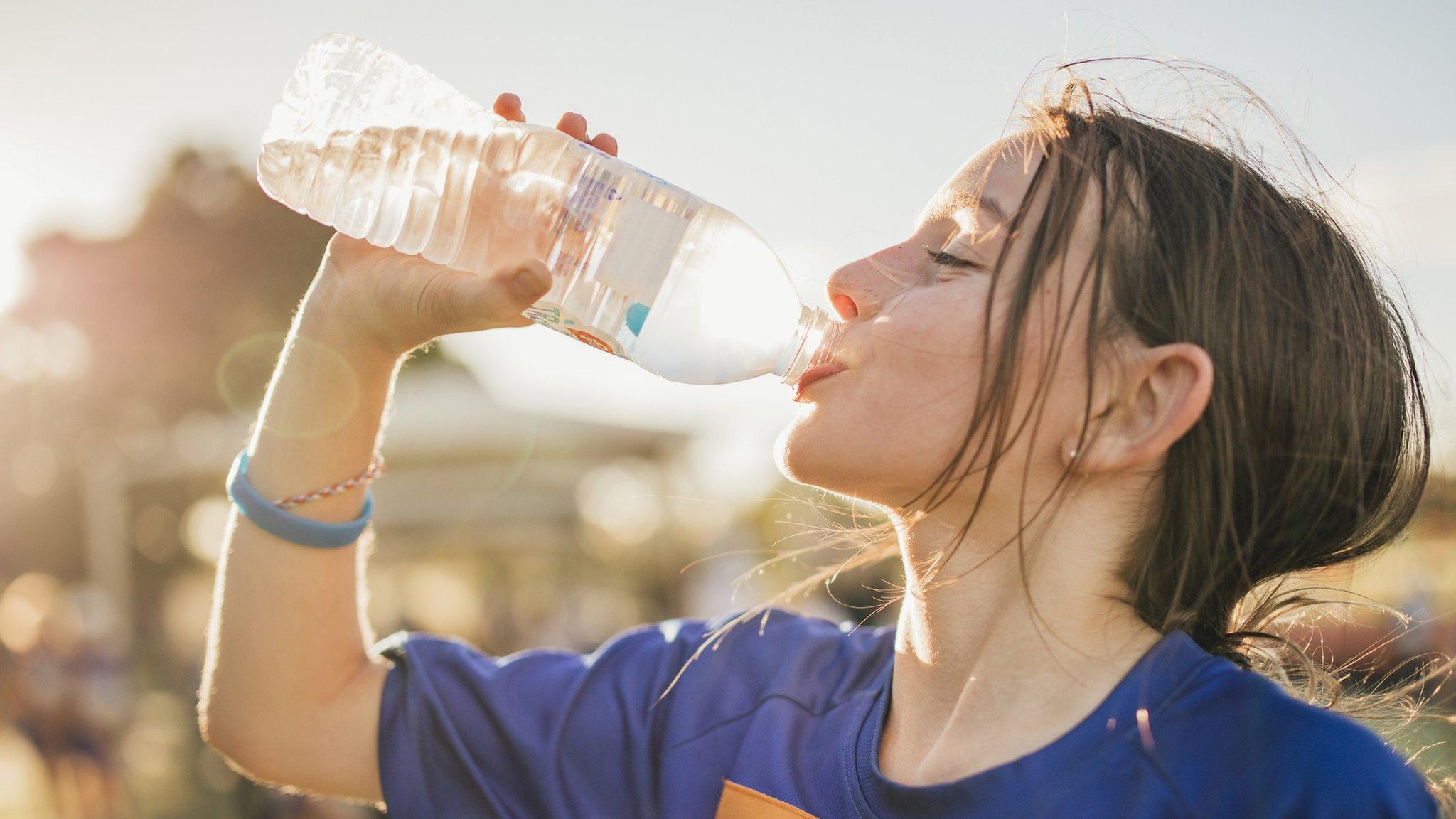 girl drinking from plastic water bottle