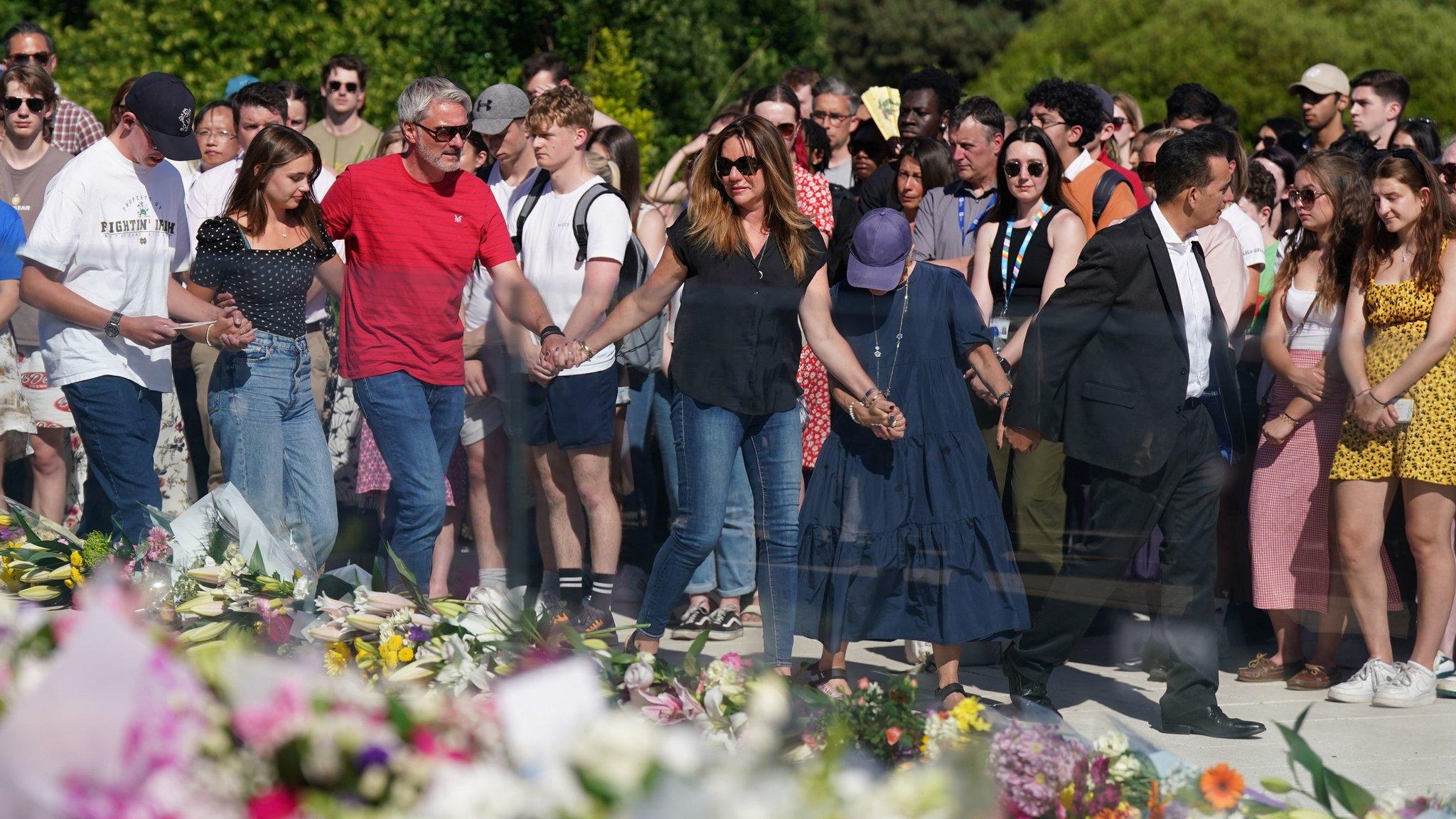 Families of students killed in attacks hold hands at vigil