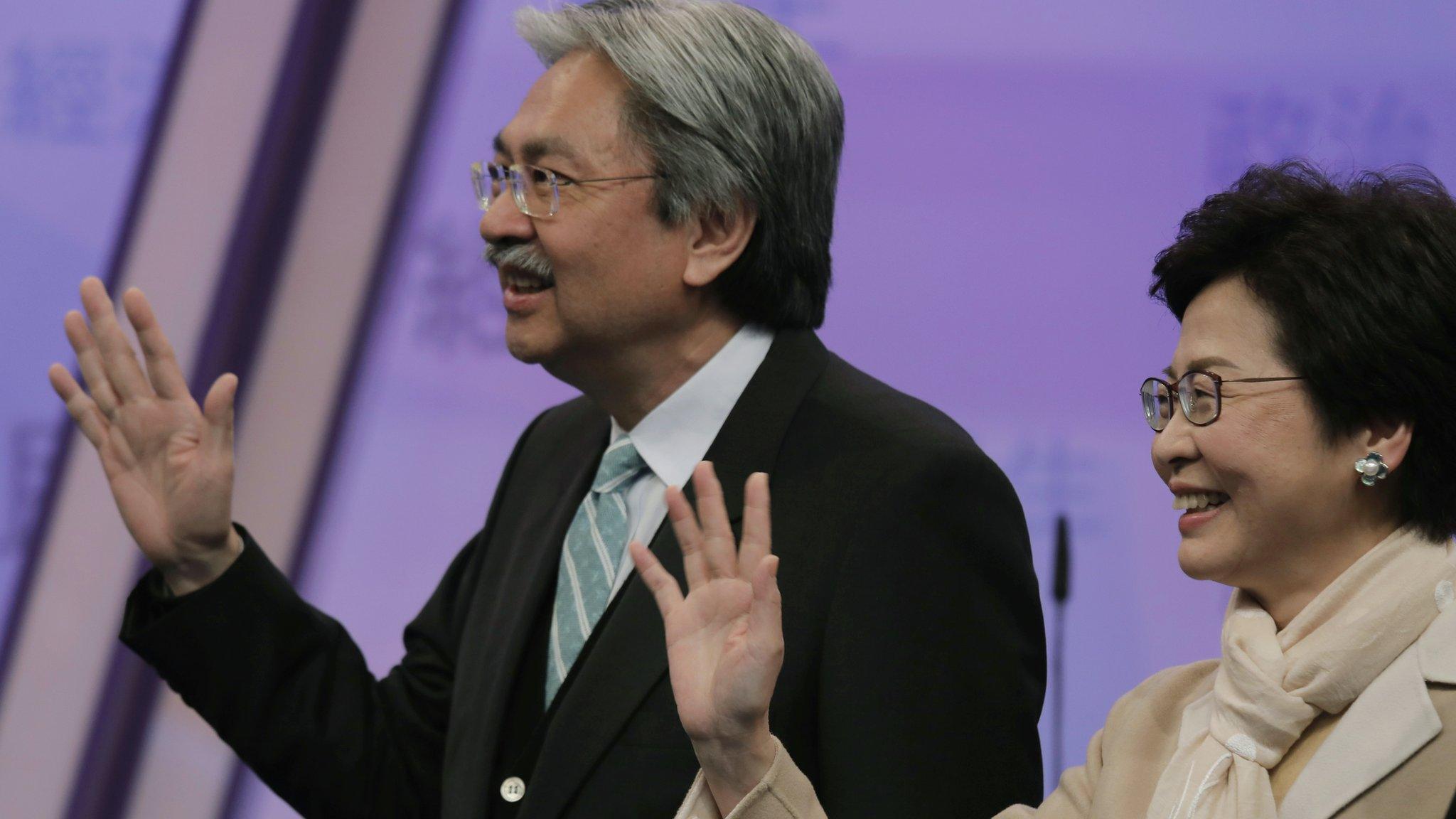 In this 14 March 2017 file photo, Hong Kong chief executive candidates, former Financial Secretary John Tsang, left, and former chief secretary Carrie Lam wave during a photo call before a chief executive election debate in Hong Kong.