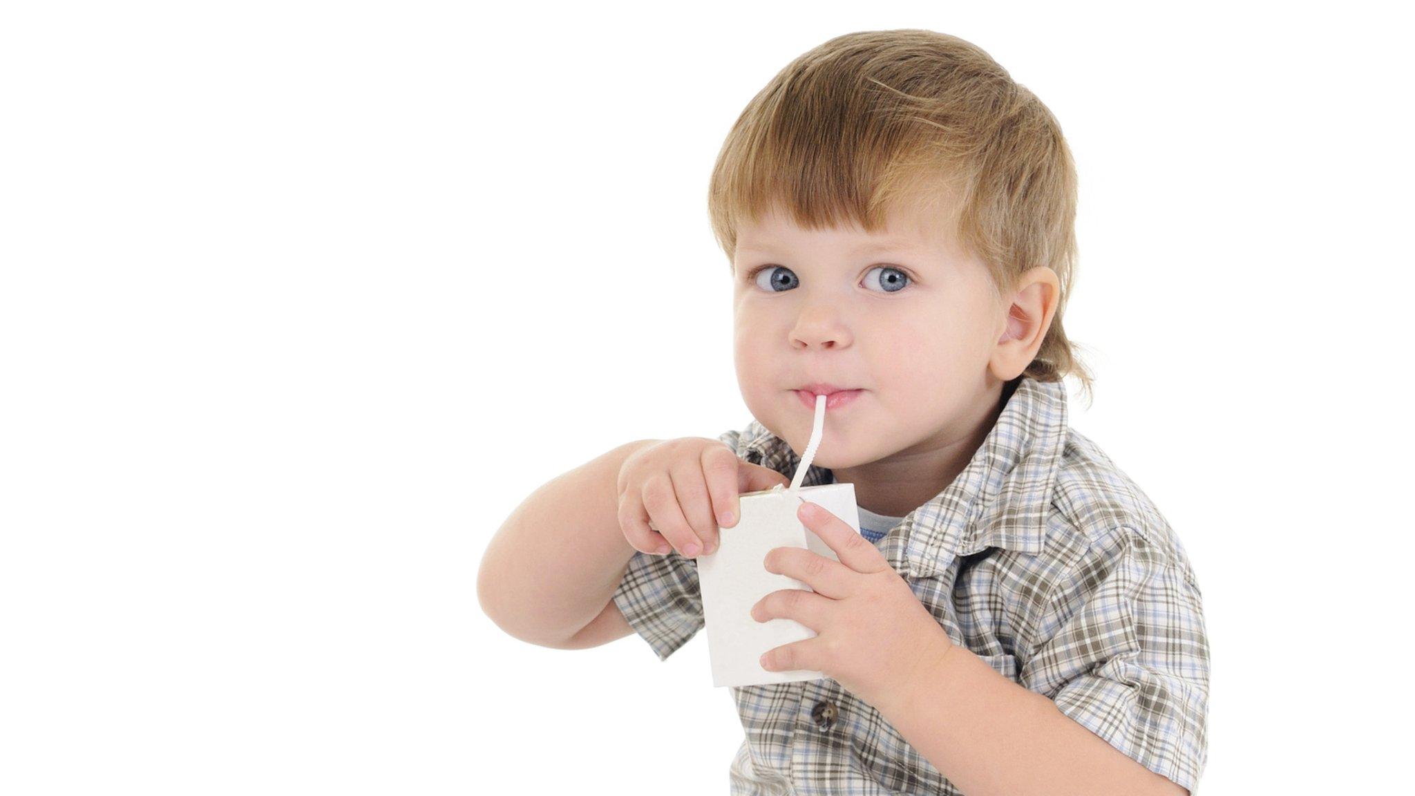 A toddler drinking from a juice carton