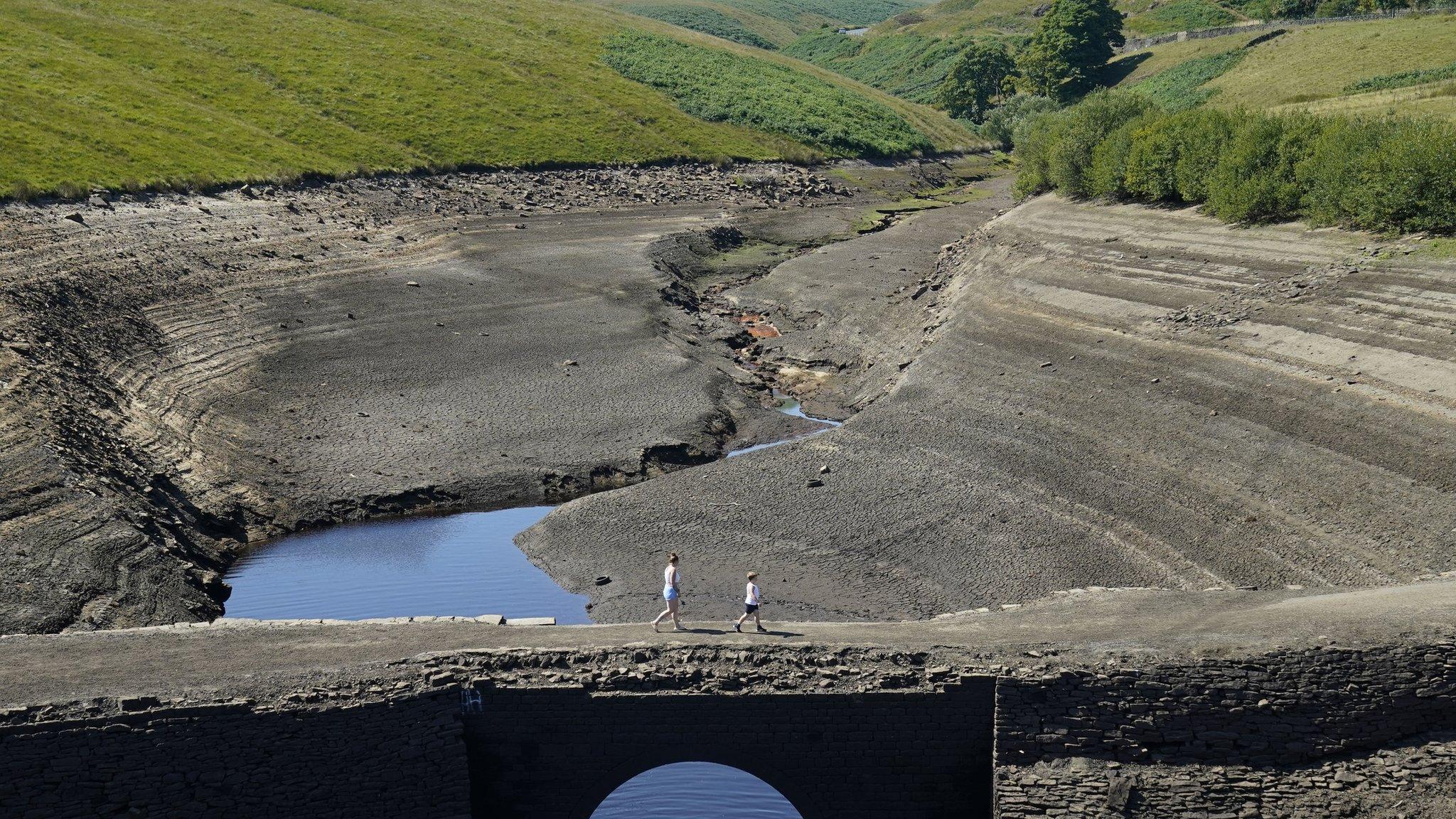 Two people walking across cracked earth at Ripponden, West Yorkshire