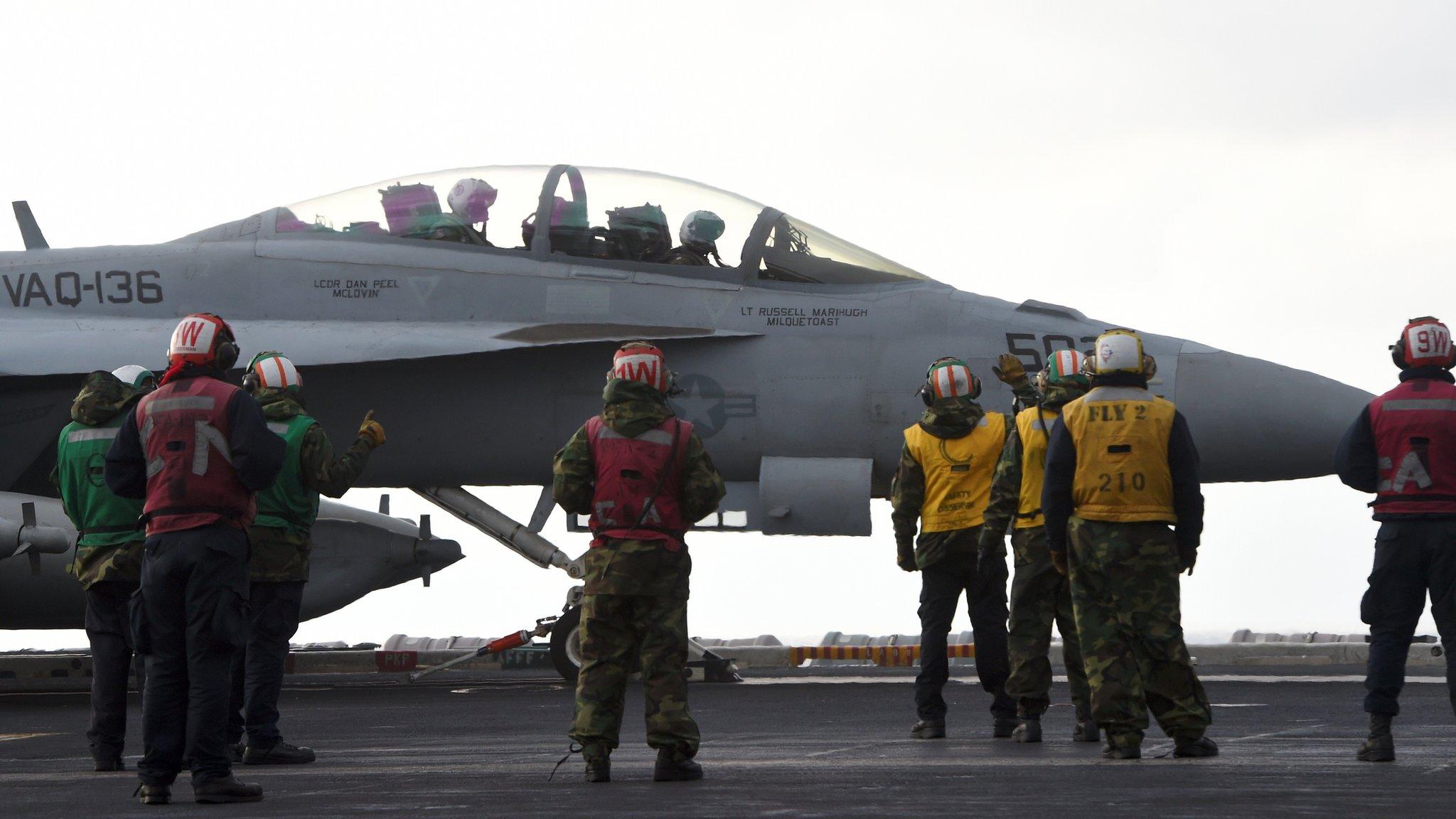 US Navy crew members stand by an EA-18G Growler electronic warfare aircraft on the deck of the Nimitz-class aircraft carrier USS Carl Vinson during a South Korea-US joint military exercise in seas east of the Korean Peninsula on 14 March 2017