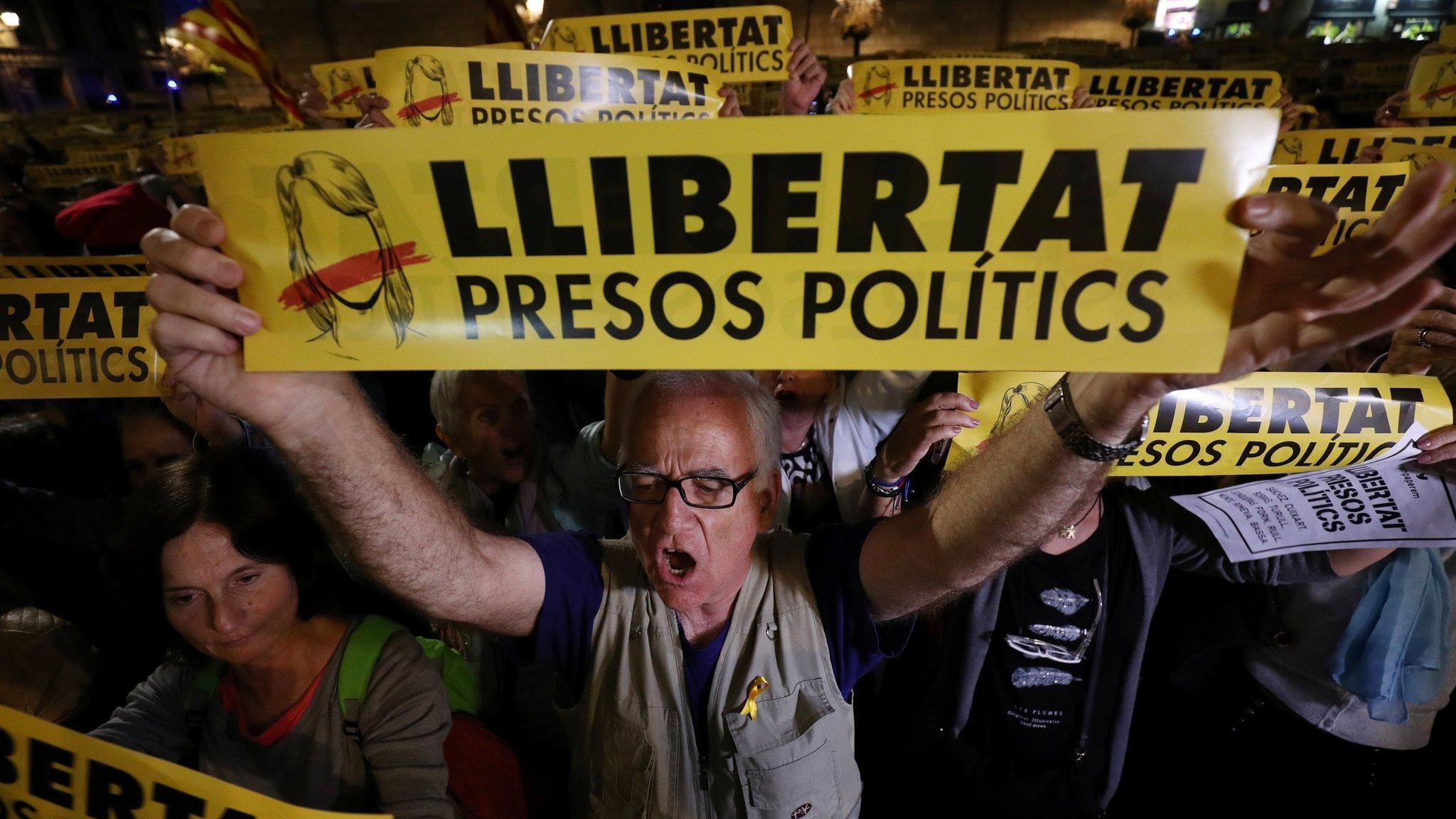 A man holds a banner reading "Freedom Political Prisoners" during a gathering in support of the members of the dismissed Catalan cabinet after a Spanish judge ordered the former Catalan leaders to be remanded in custody pending an investigation into Catalonia's independence push