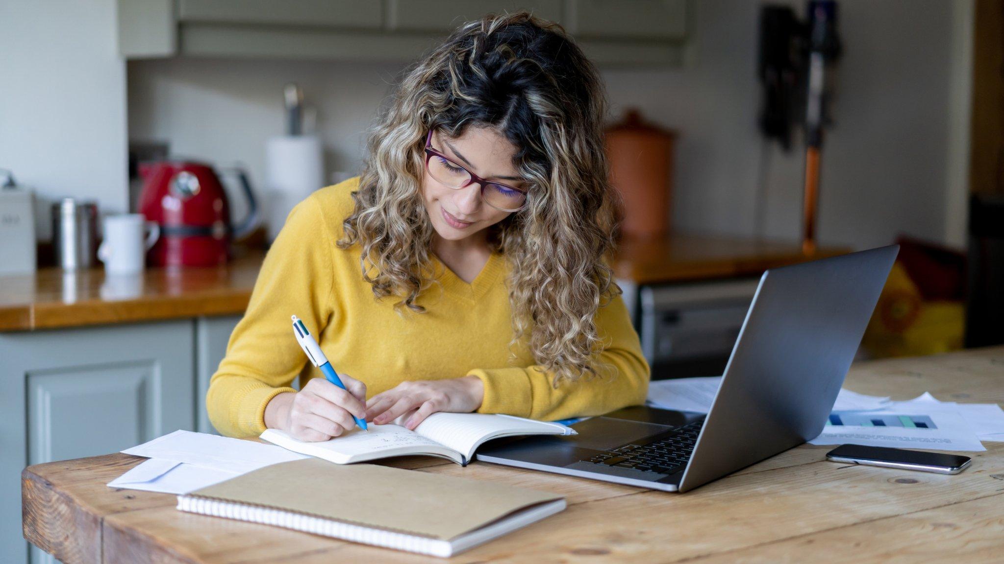 Woman working from home at kitchen table.