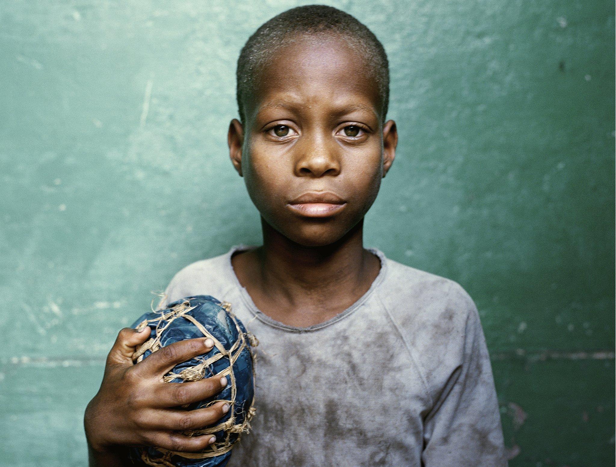 Mozambique: A boy holds a football he has made from tree bark held together with rope. The photo from 'Women Behind the Football Lens,' is part of 'The Game', an exhibition at the National Football Museum, showcasing football cultures around the world.