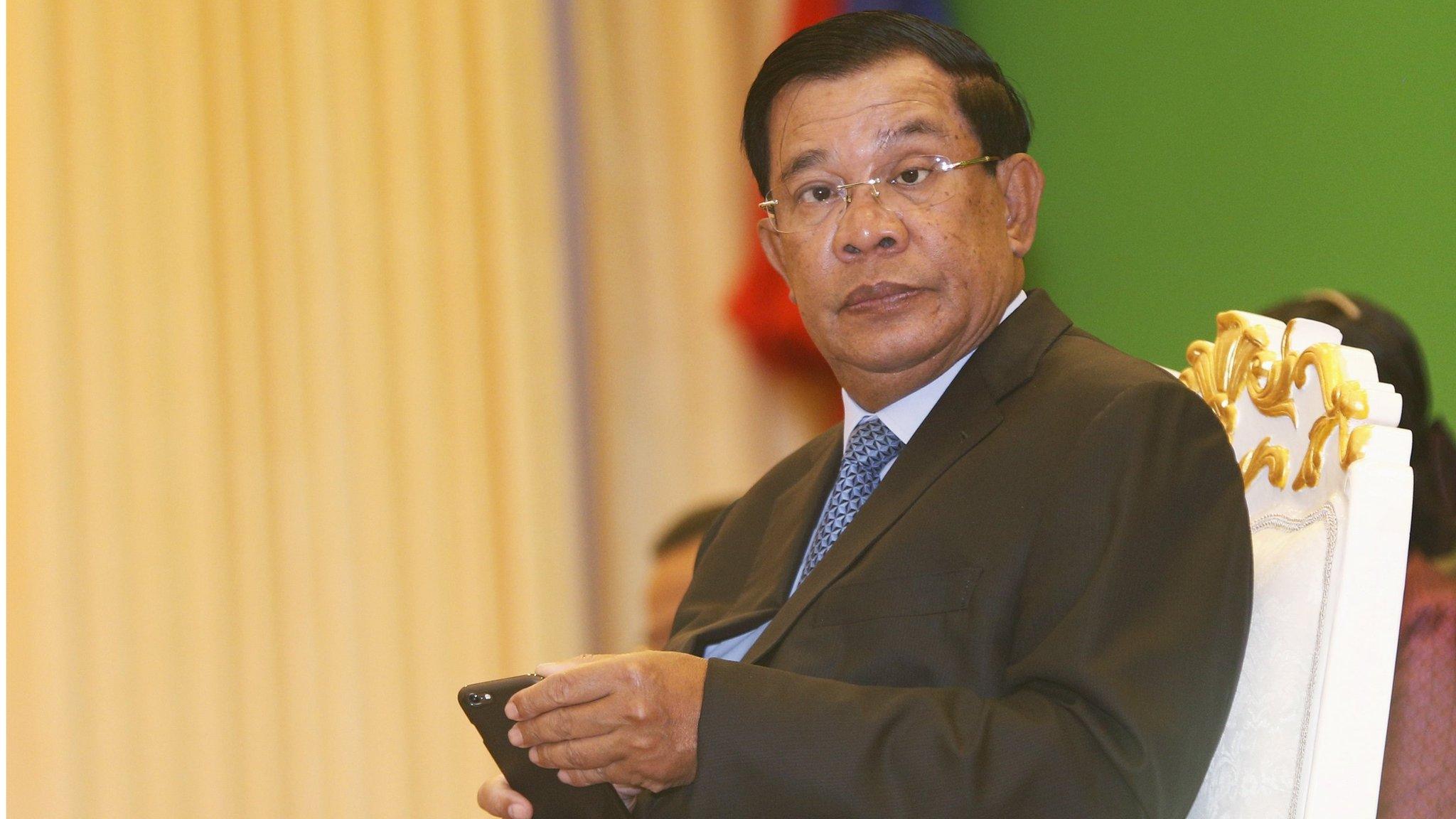 Hun Sen looks up from his smart phone at a ceremony in Phnom Penh on 25 February 2016