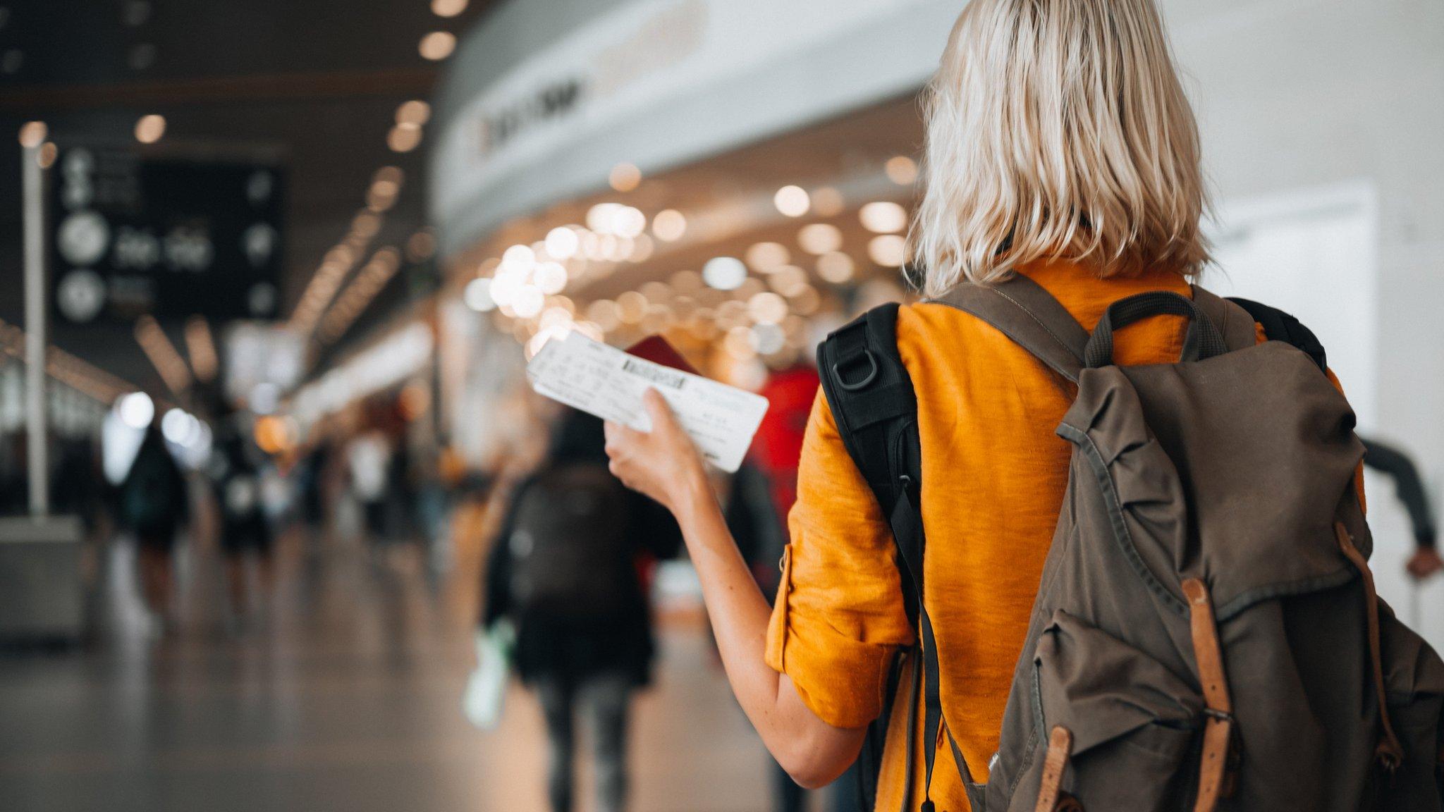 Woman at the airport holding a passport with a boarding pass.