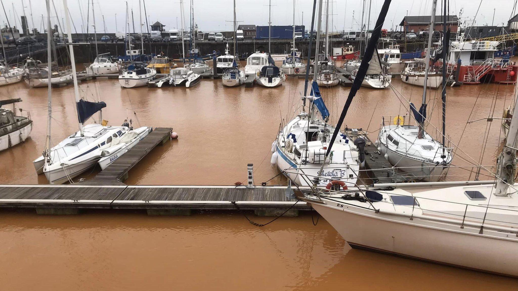 Wide view of orange / rust coloured water in Whitehaven Harbour