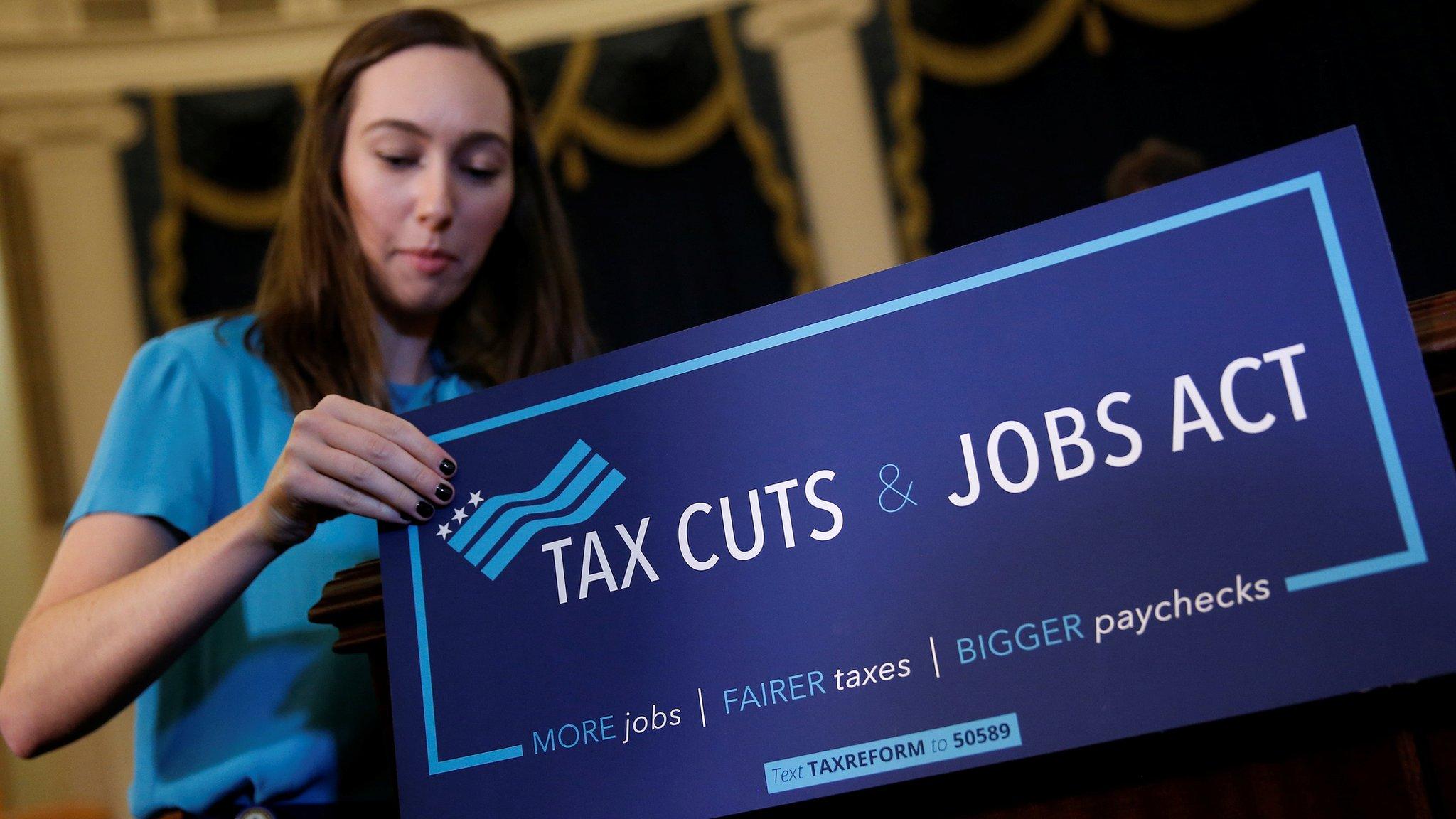 A congressional aide places a placard on a podium for the House Republican's legislation to overhaul the tax code