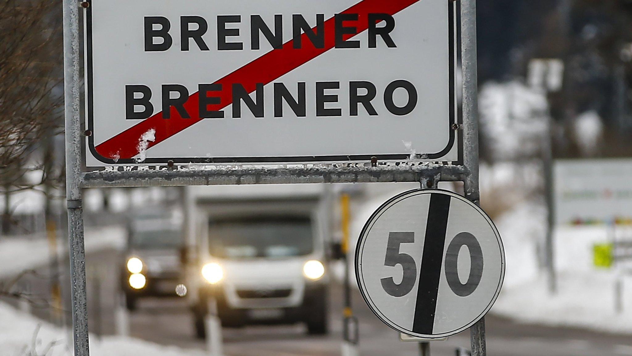 Cars drive along a street with a sign reading "Brenner-Brennero" in the Italian village of Brenner on the Italian-Austrian border