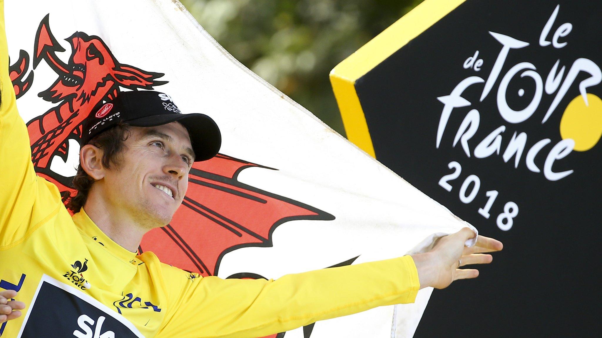 Geraint Thomas holding Welsh flag by Tour de France sign