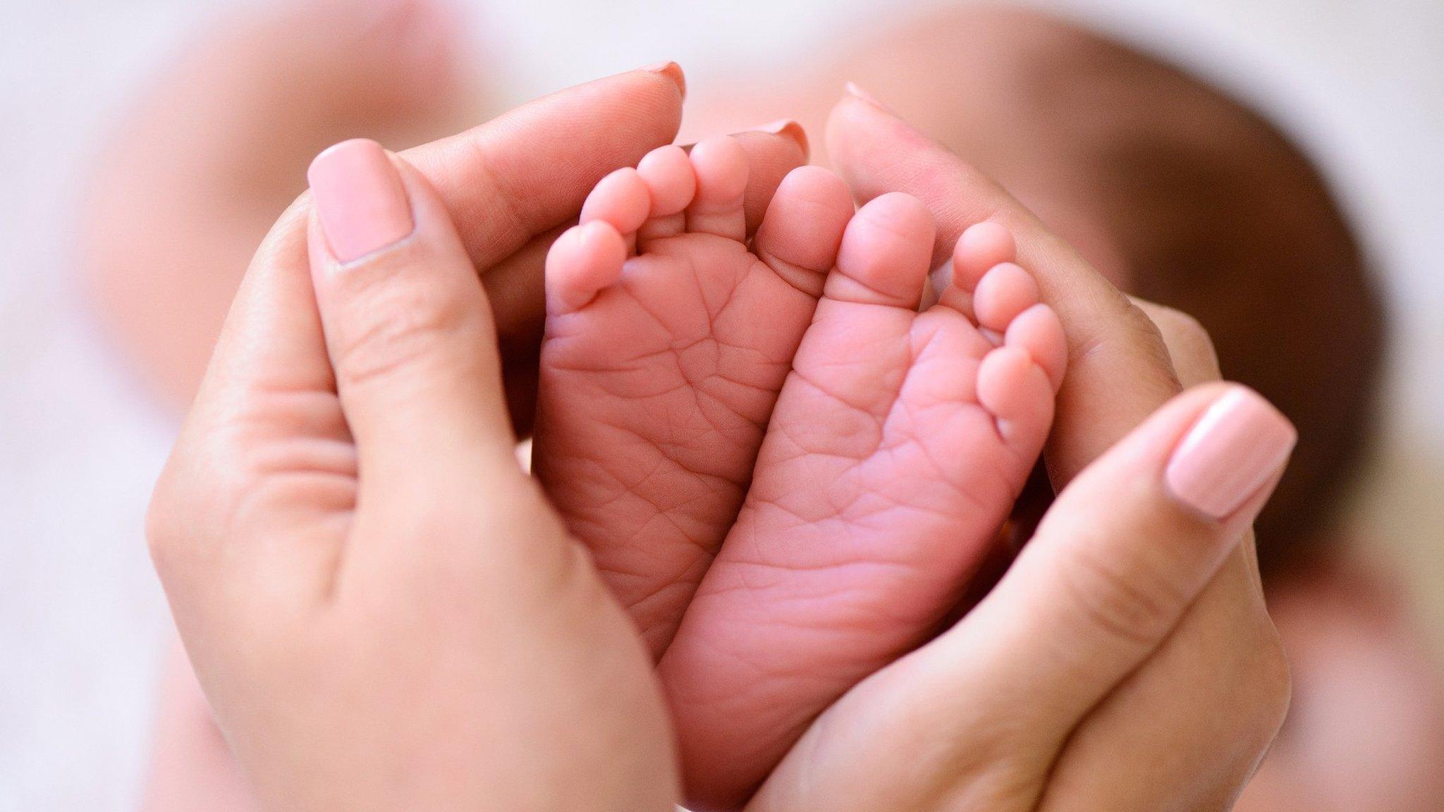 Baby's feet between adult hands