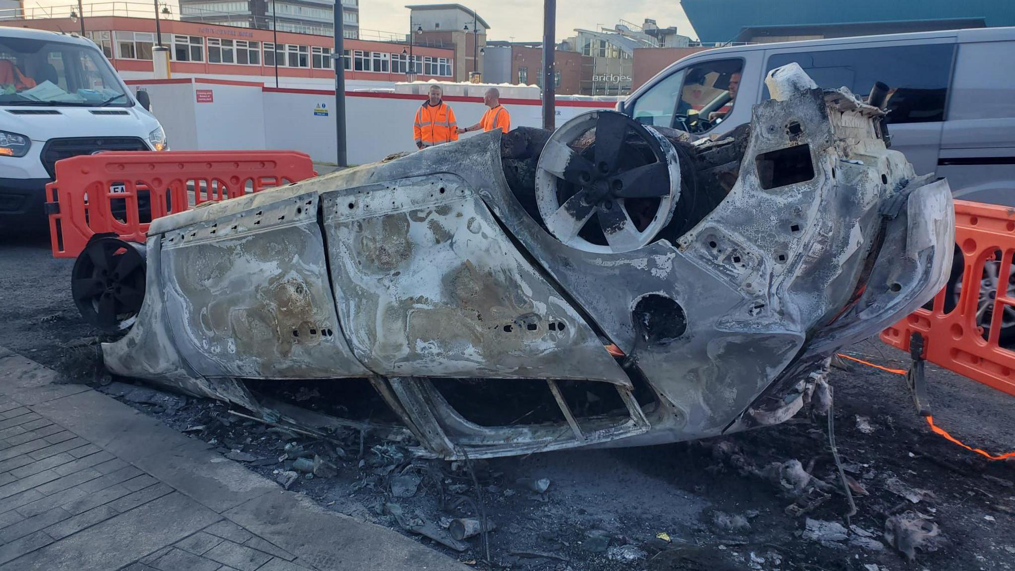 A burnt out car upside down pictured during the day