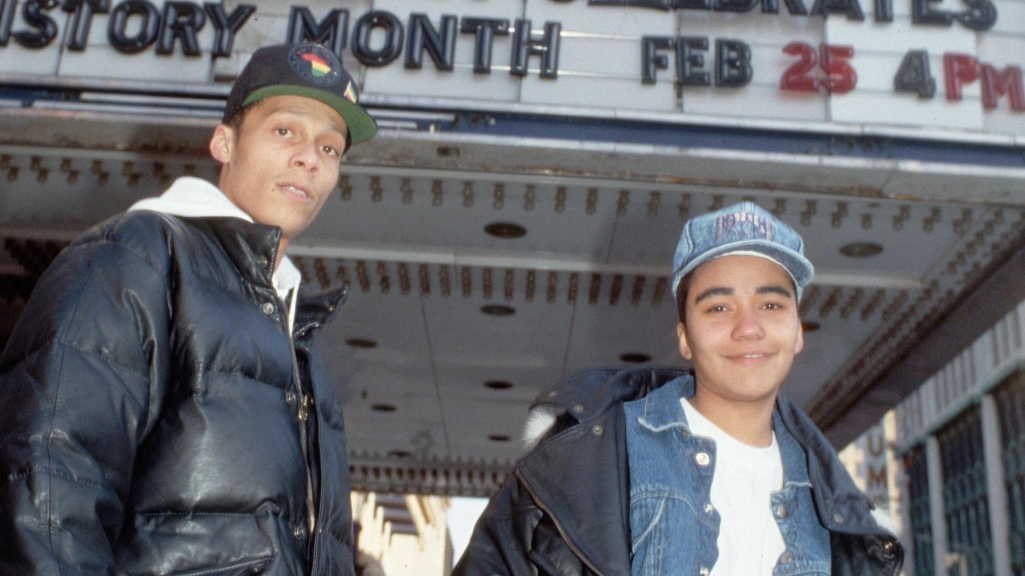 Two young Technotronic rappers stand in front of a theatre marquee