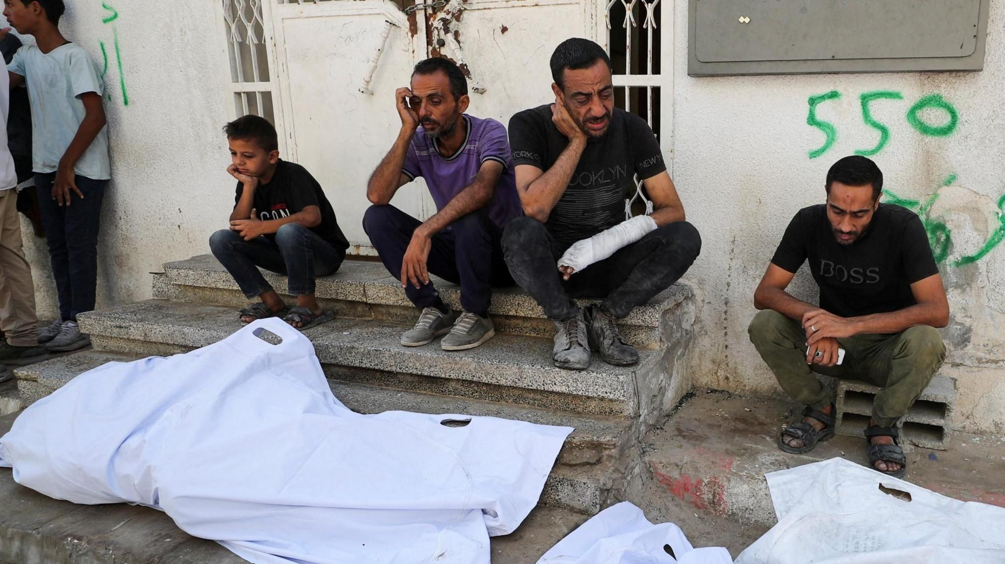 Mourners sit next to the bodies of Palestinians killed in overnight Israeli strikes, outside al-Shifa Hospital in Gaza City (2 September 2025)