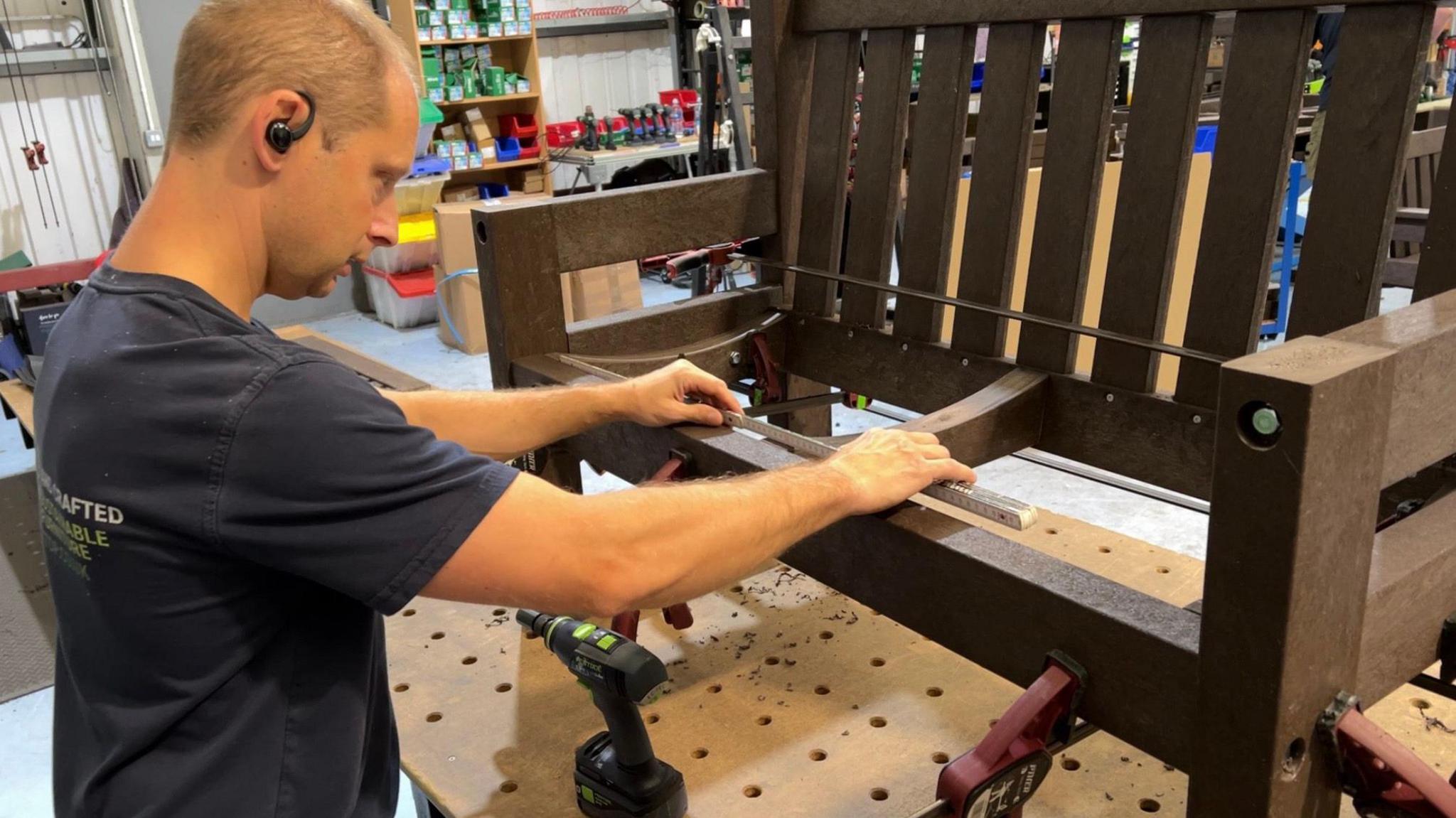 A factory worker making a bench out of recycled plastic