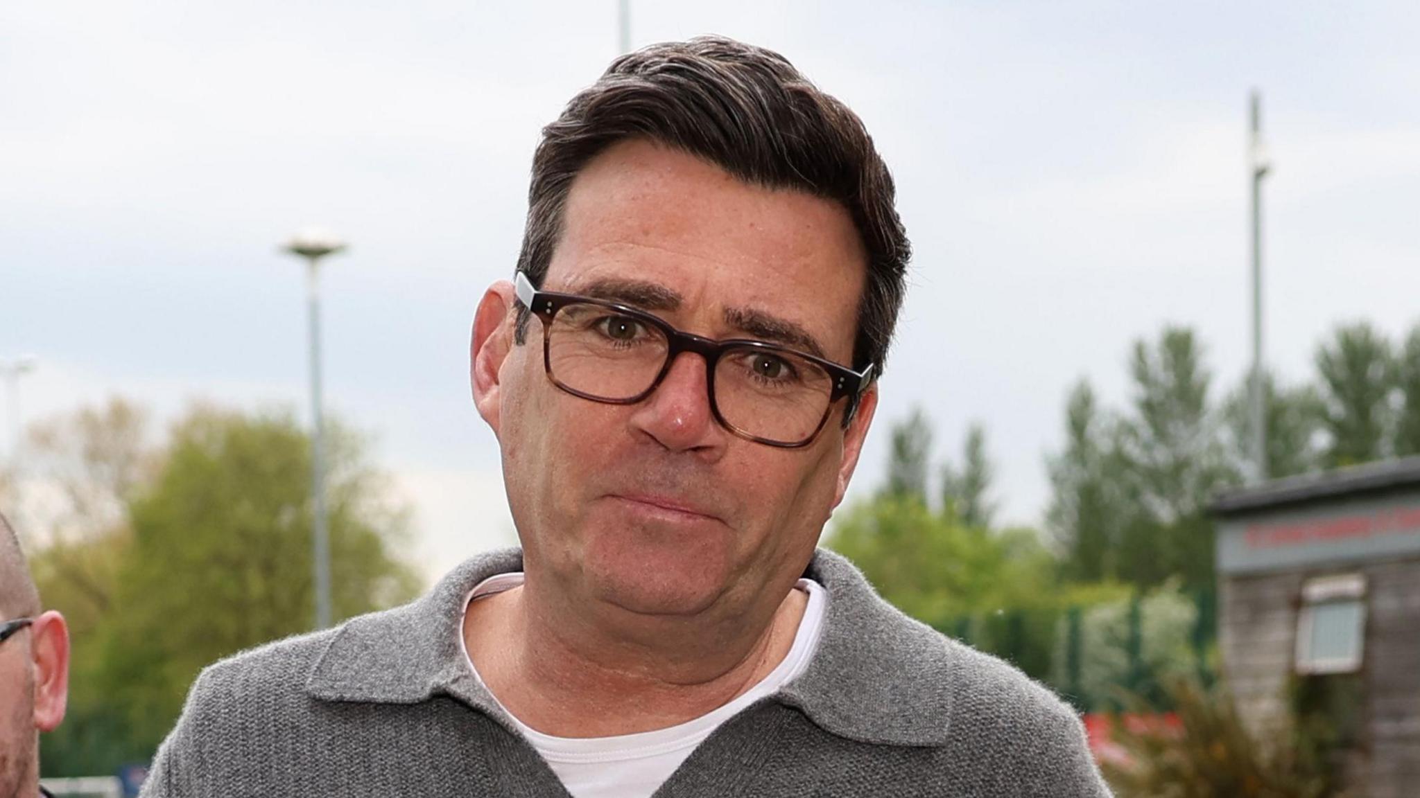 Andy Burnham me një pulovër gri dhe bluzë të bardhë duke mbërritur për një ndeshje bamirësie futbolli