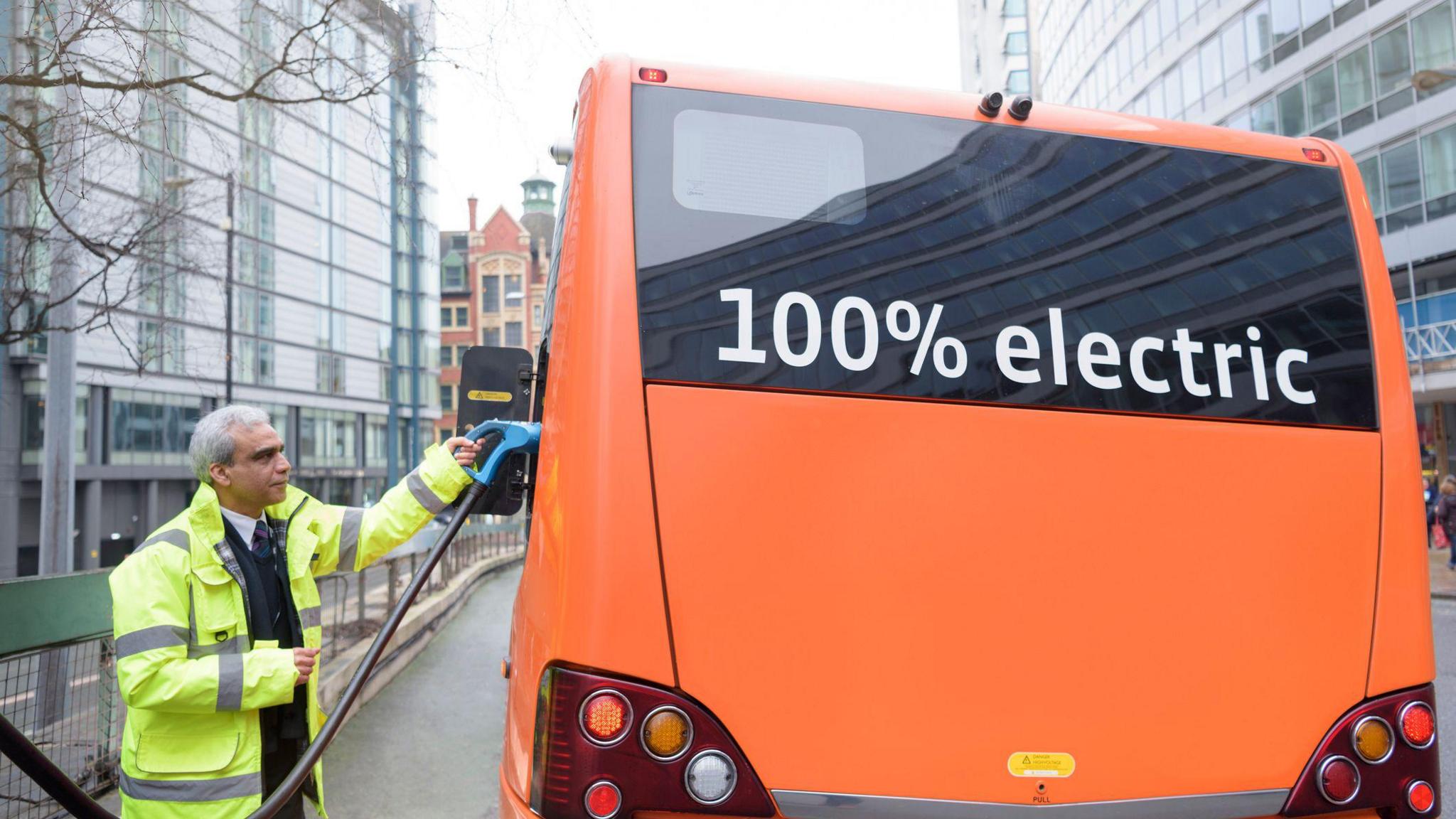 Bus driver charging electric bus at charging station