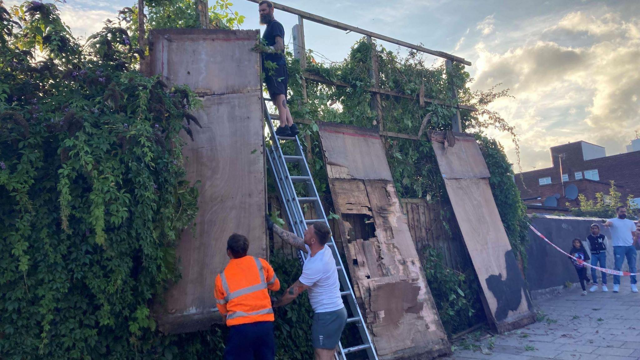 Contractors dismantling a billboard in Cricklewood adorned with Banky's stretching cat 