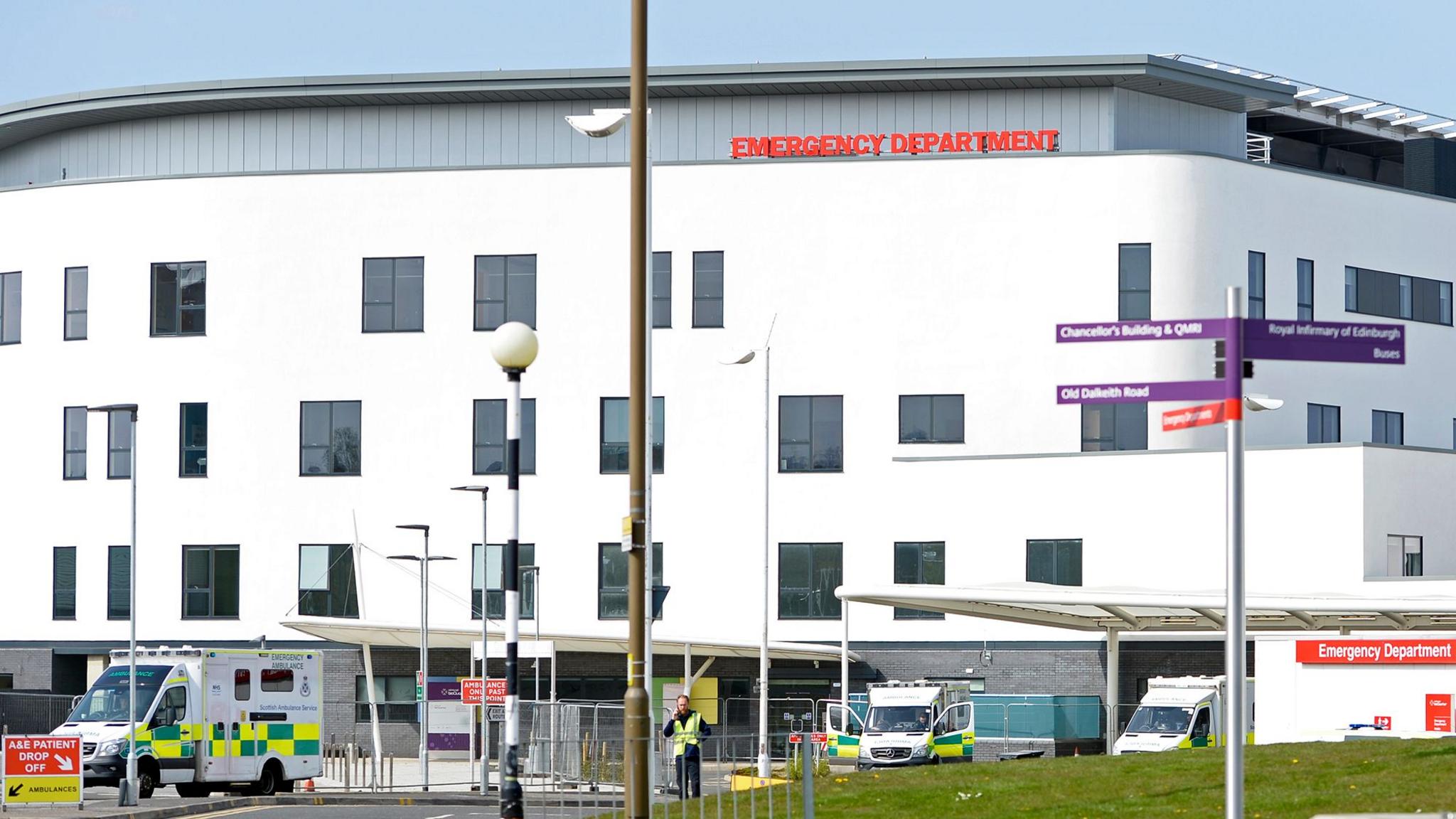 A large white building with ambulances parked outside