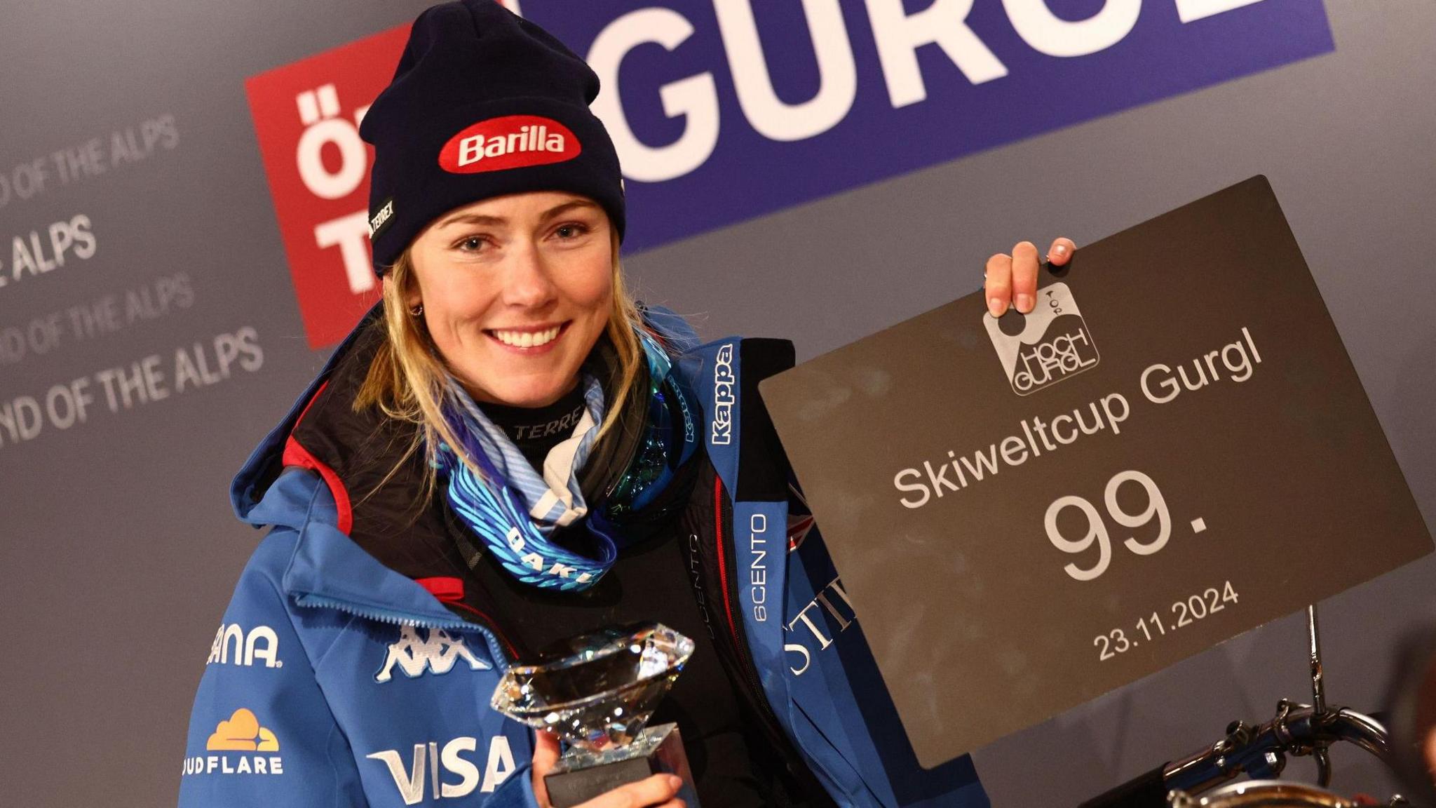 Mikaela Shiffrin holds up a sign about her 99th World Cup win