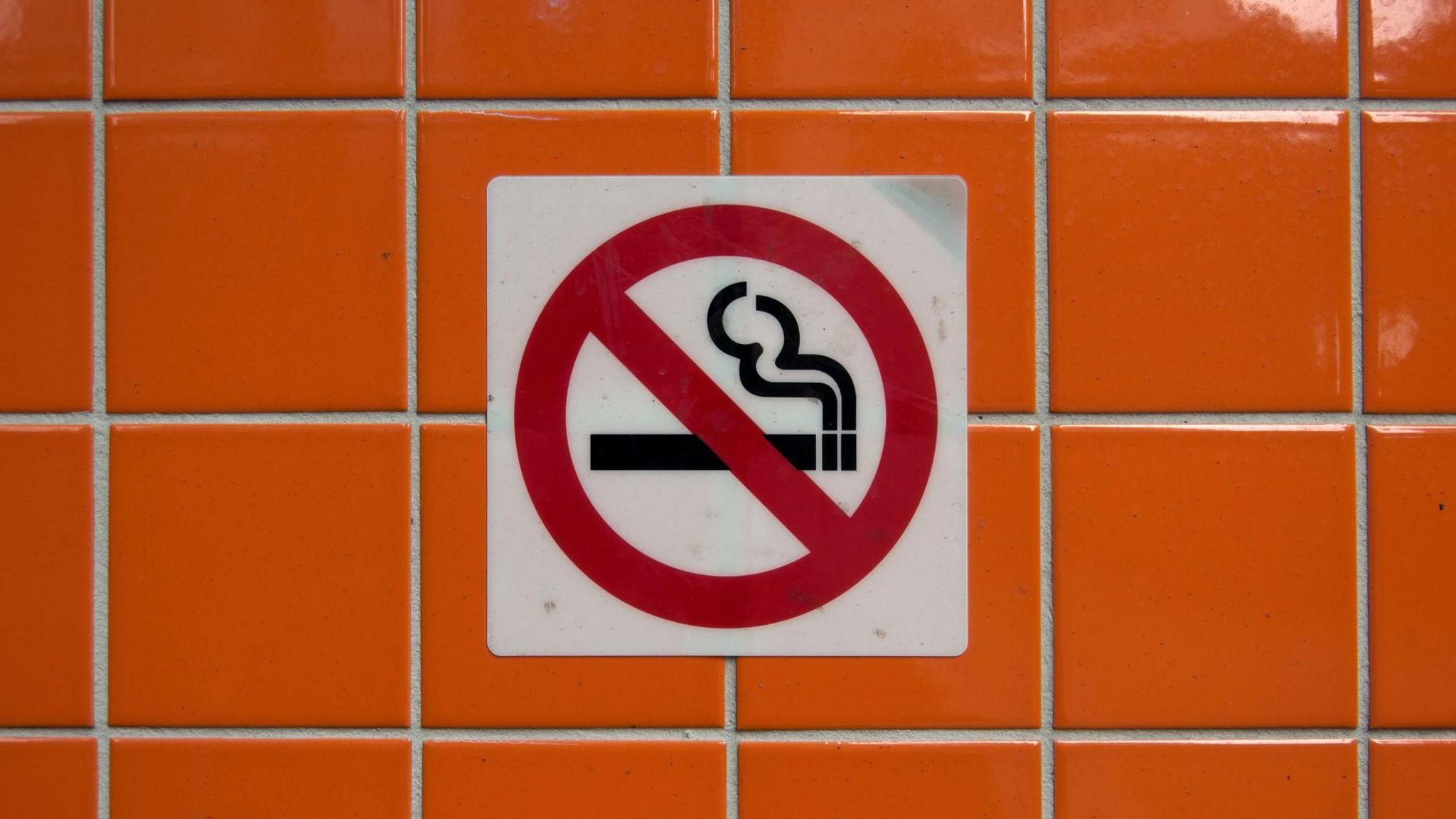 a brightly tiled wall with a sign that says smoking is not allowed